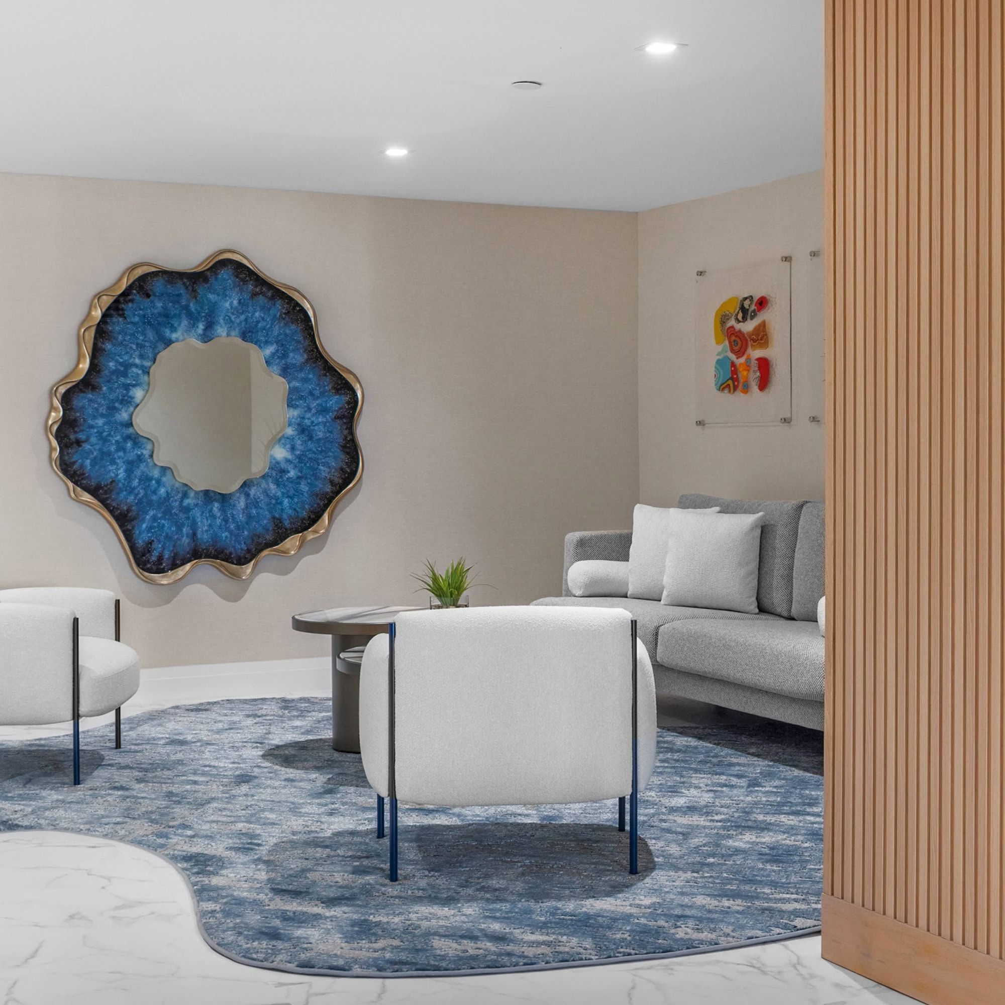 Elegant lobby seating area with modern white chairs and artistic wall mirror, showcasing luxury furnishings.