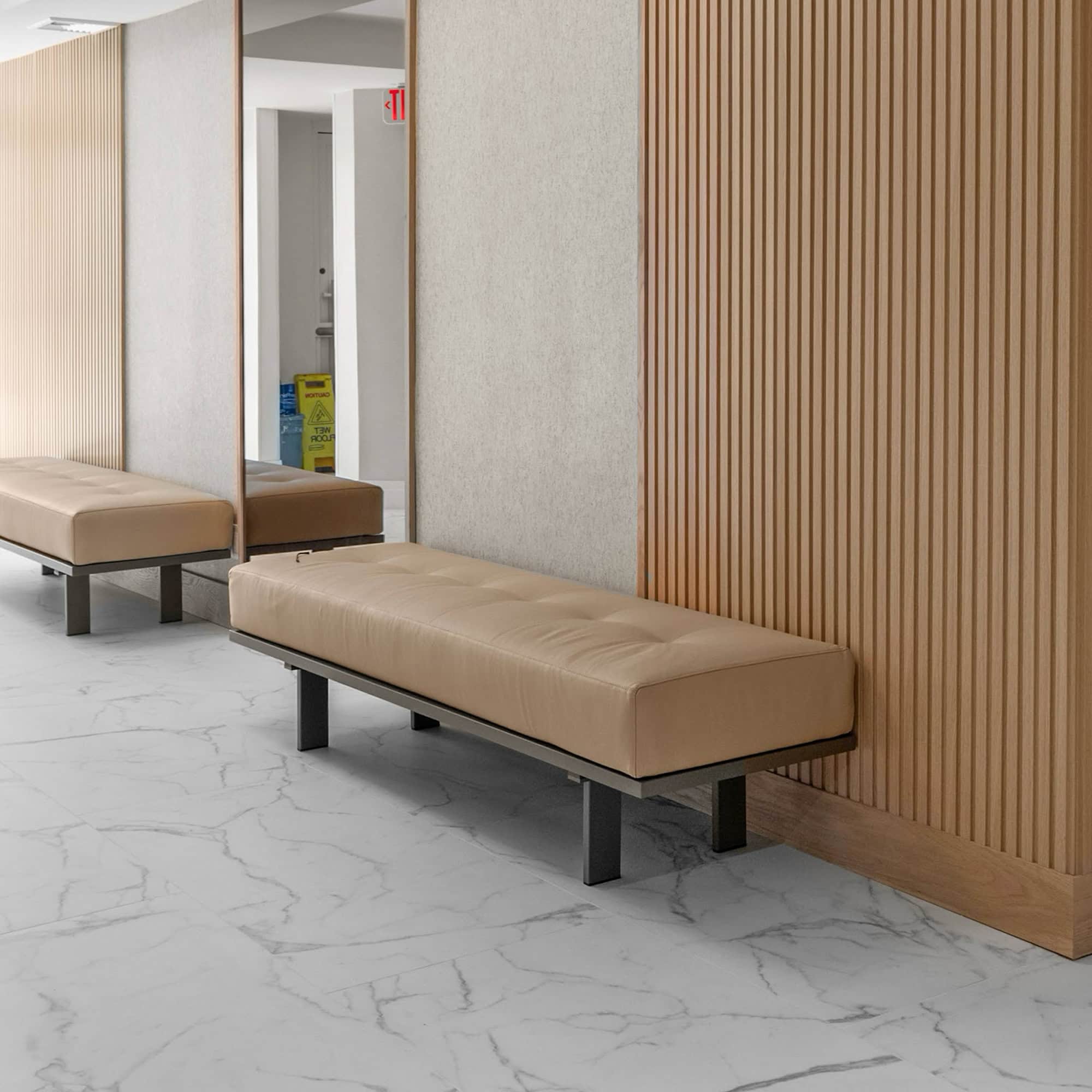 Contemporary lobby seating with beige upholstered benches and wood-paneled accent walls.