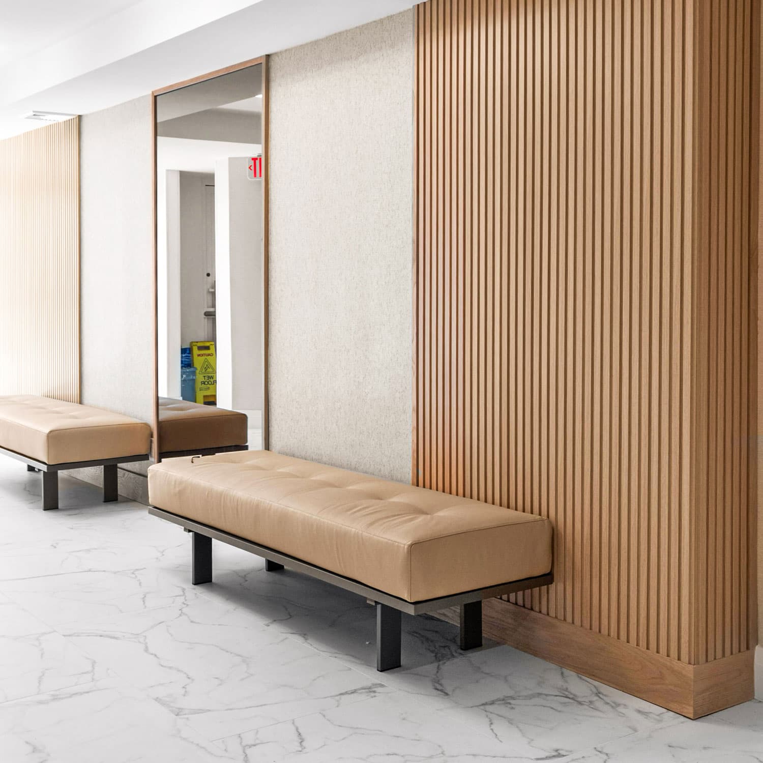 Contemporary lobby seating with beige upholstered benches and wood-paneled accent walls.