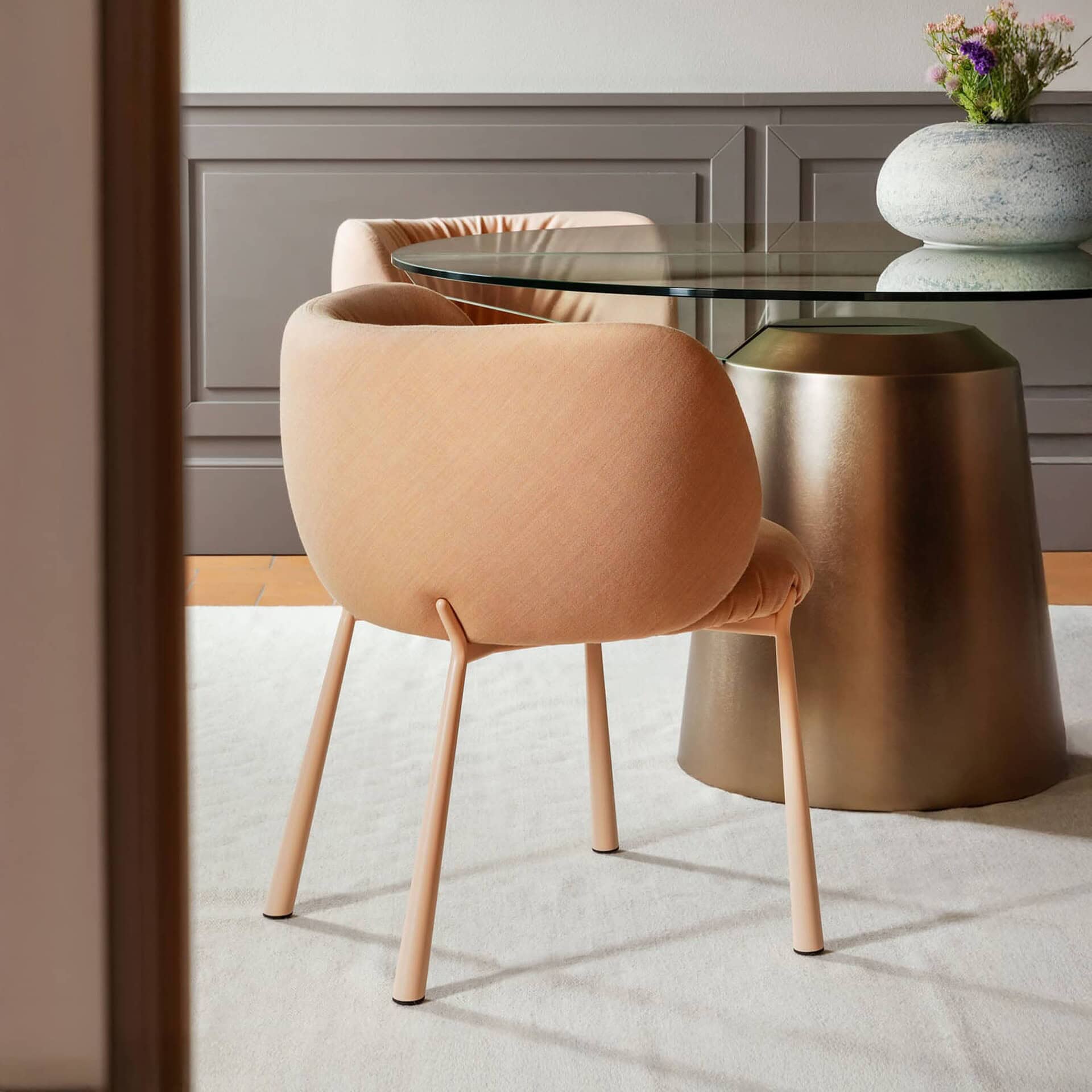 Soft peach upholstered dining chair with metal legs in modern interior setting.