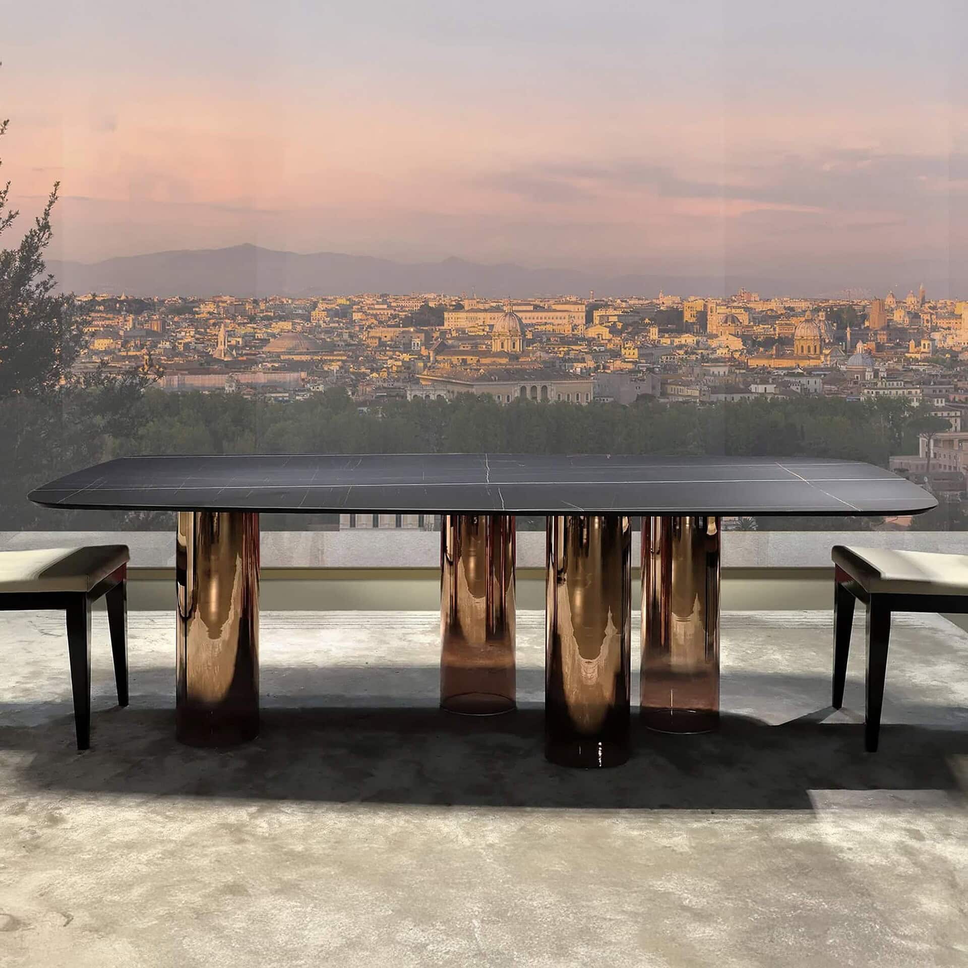 Luxury modern dining table with glass top and bronze glass base, skyline view setting.