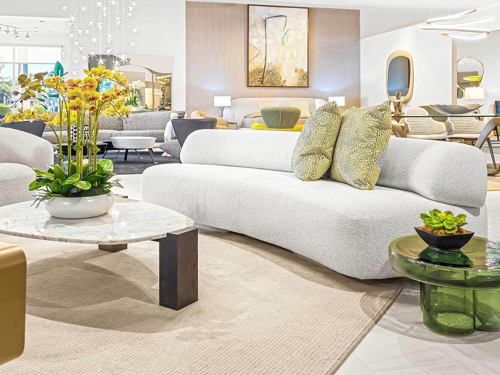 Luxurious white sofa with green patterned pillows in a modern, stylish living room.