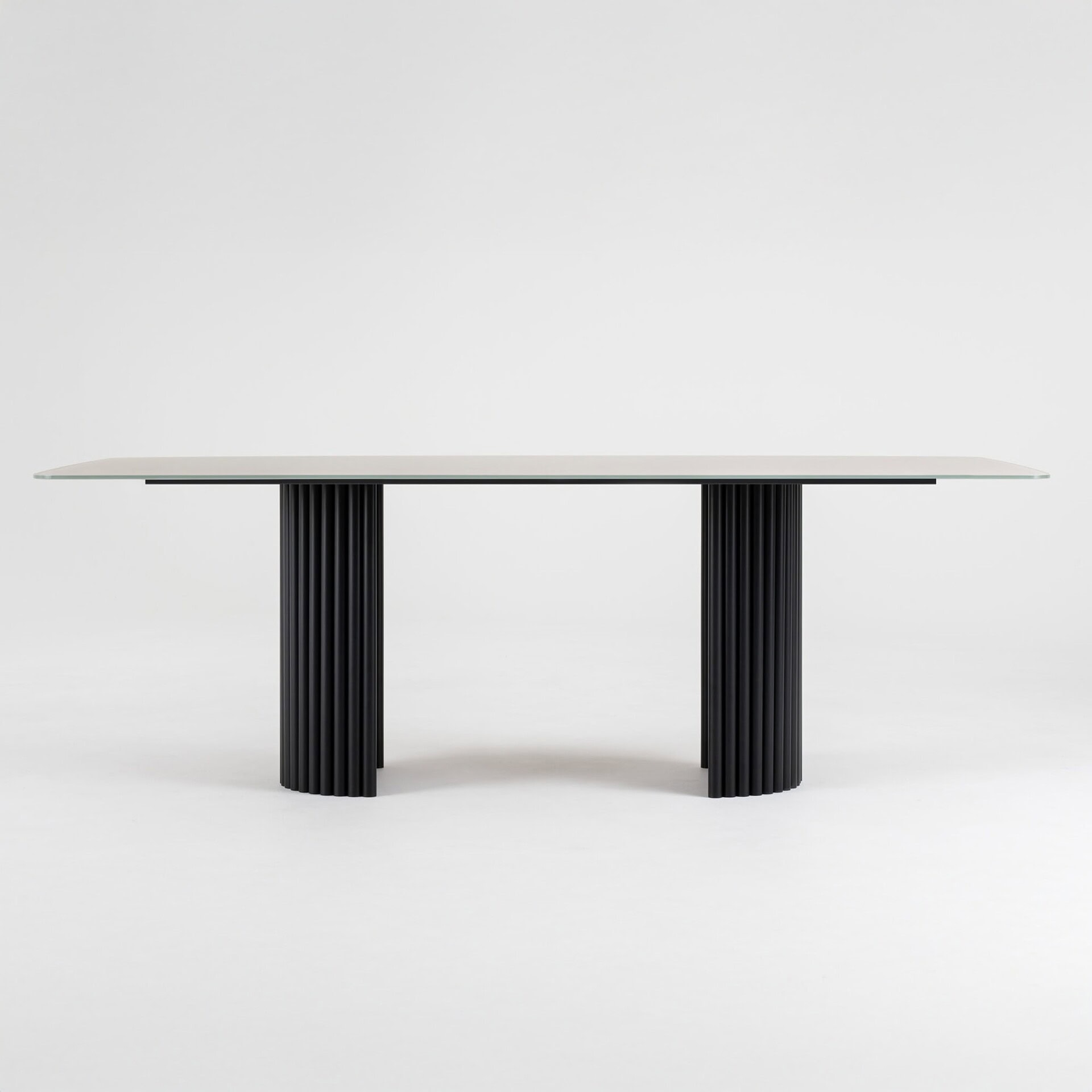 Stylish, contemporary dining table featuring sleek black fluted legs and a minimalist glass top. Perfect for upscale home decor.