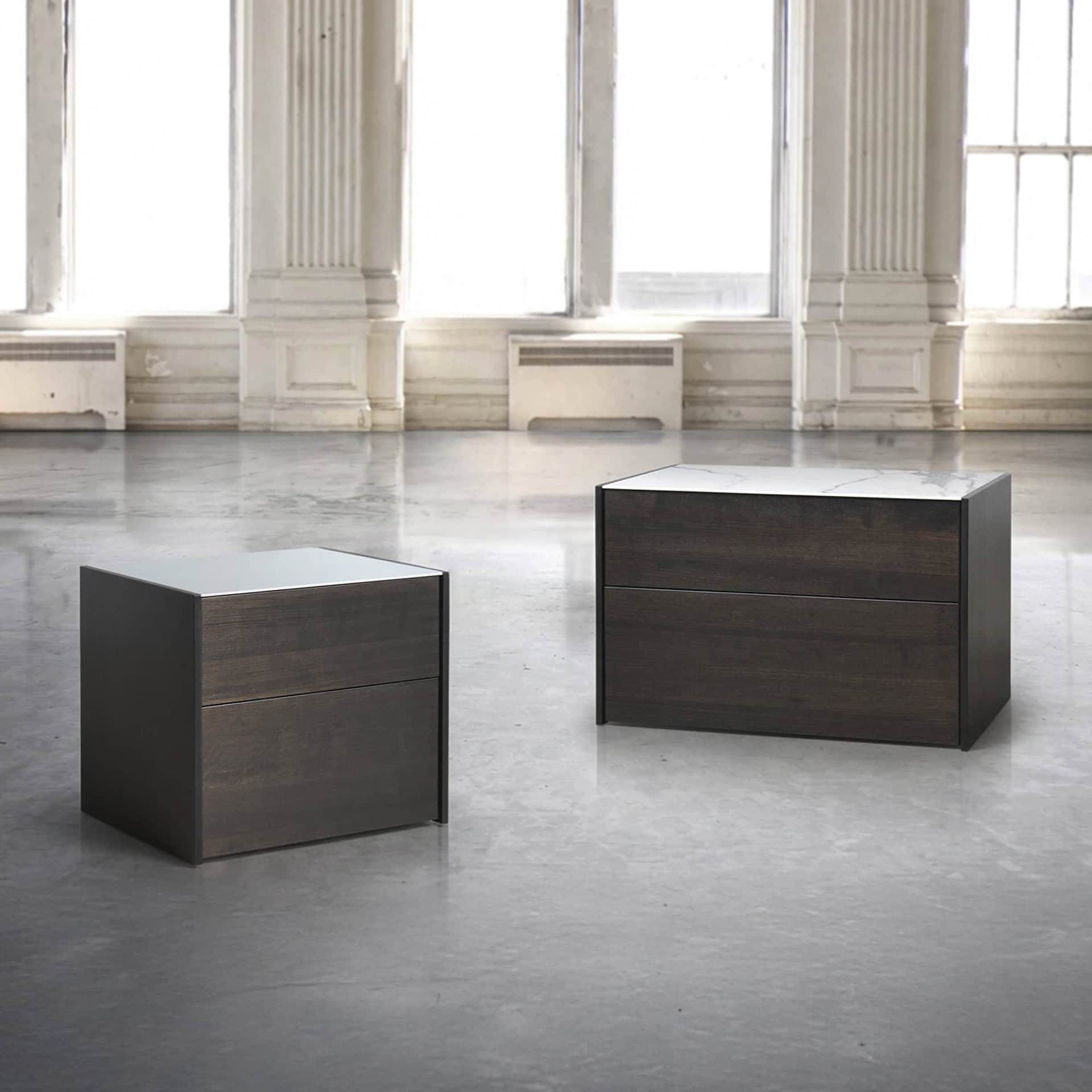 Contemporary dark wood and marble accent tables in a spacious, bright interior setting.