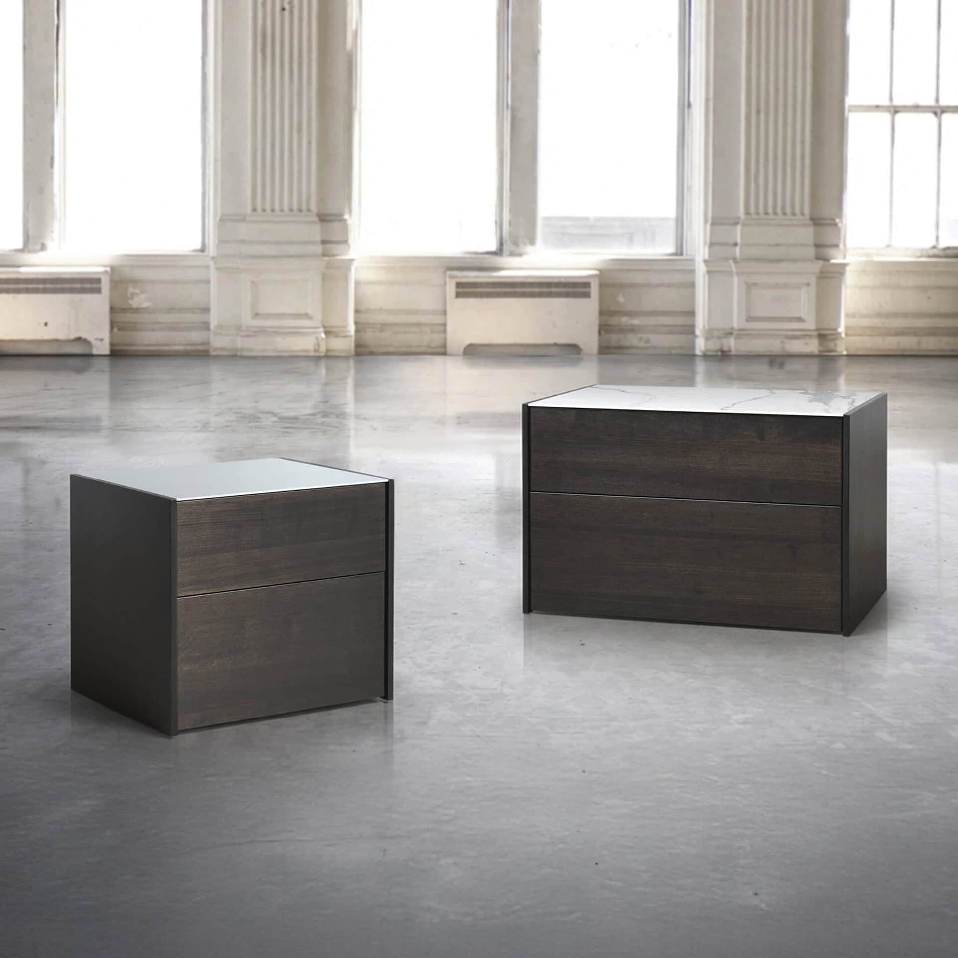 Contemporary dark wood and marble accent tables in a spacious, bright interior setting.