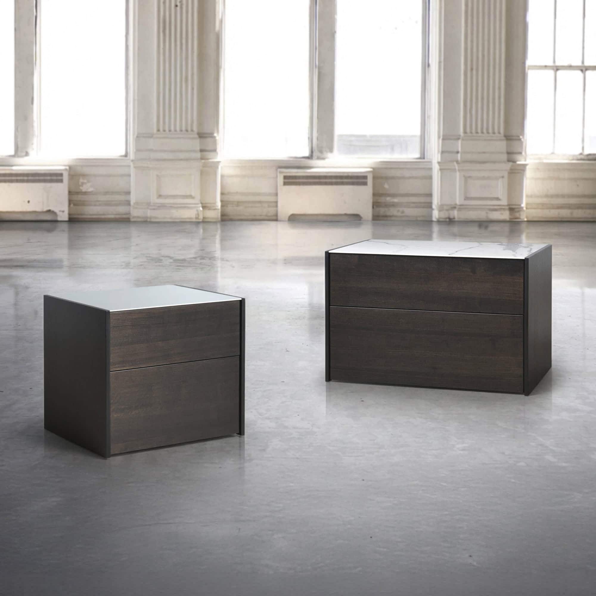 Contemporary dark wood and marble accent tables in a spacious, bright interior setting.