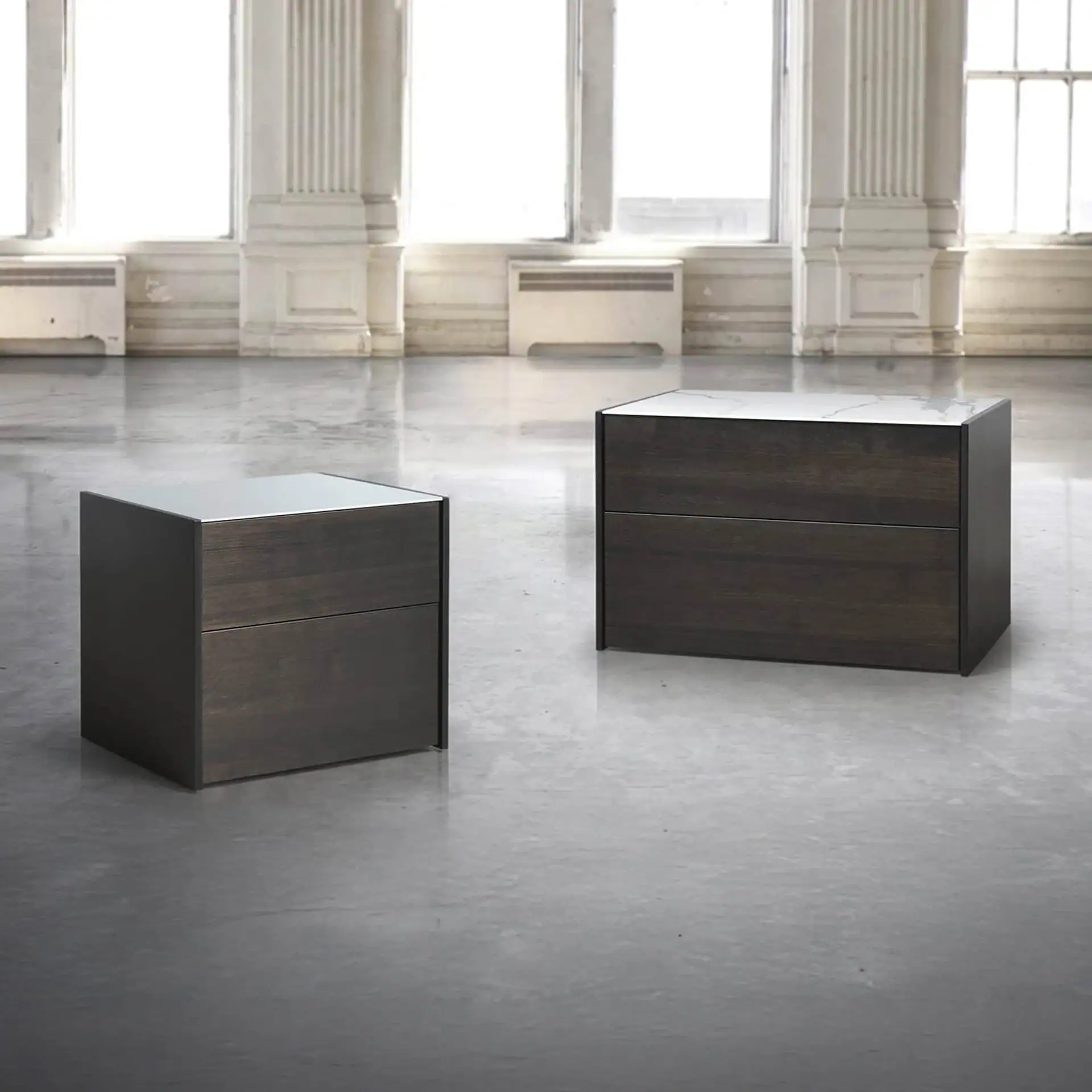 Contemporary dark wood and marble accent tables in a spacious, bright interior setting.