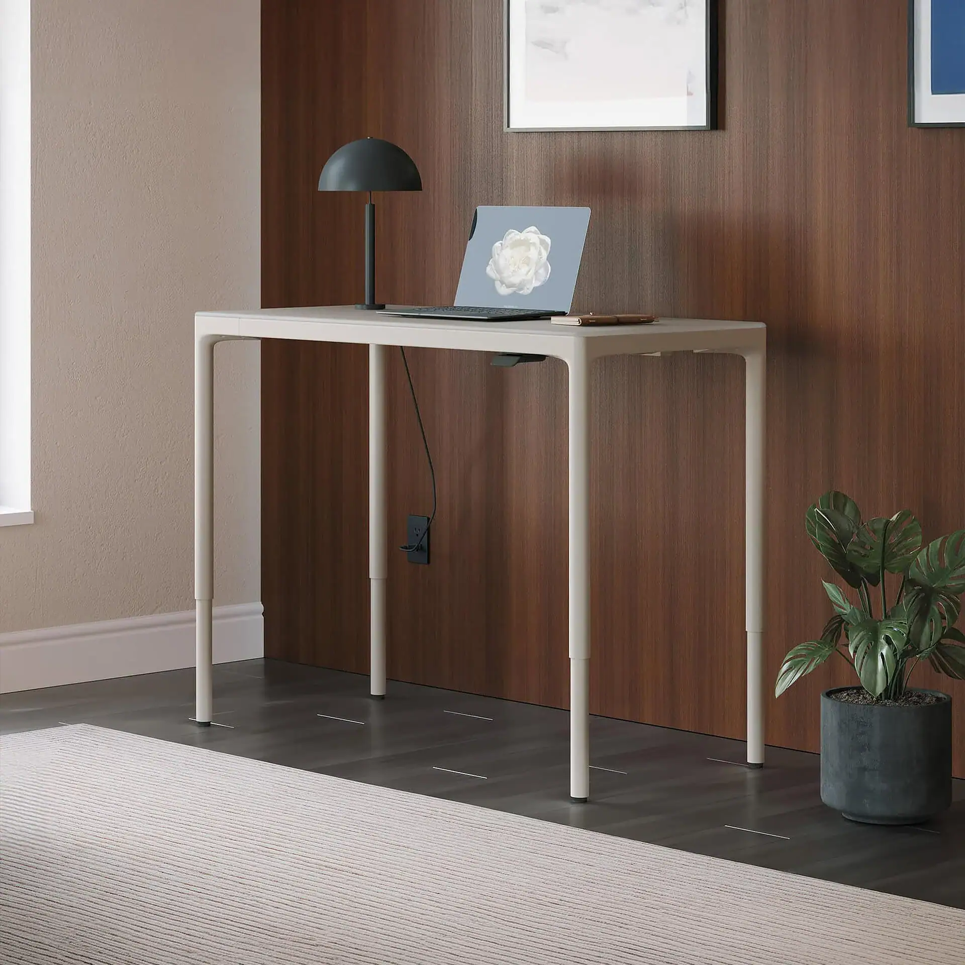 Modern white height-adjustable standing desk with a laptop and desk lamp.