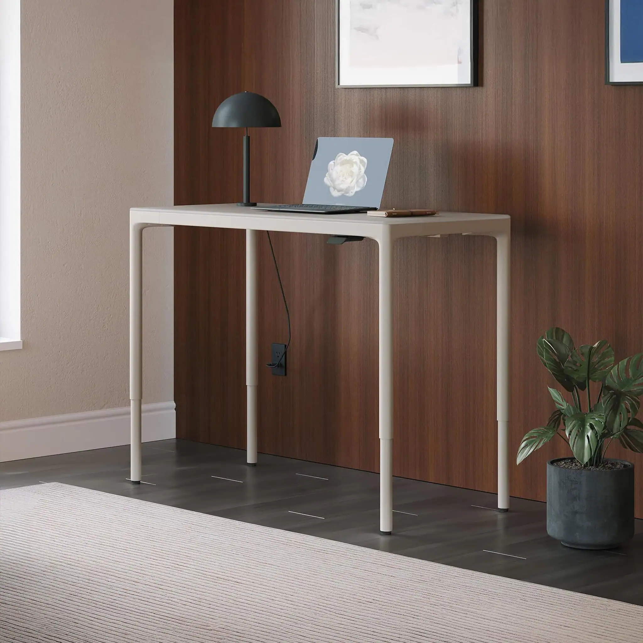 Modern white height-adjustable standing desk with a laptop and desk lamp.