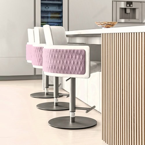 Three modern bar stools with light gray upholstery and quilted pink diamond-patterned armrests, lined up against a white kitchen counter with a vertical slatted wood panel. A decorative stone bowl sits on the counter.