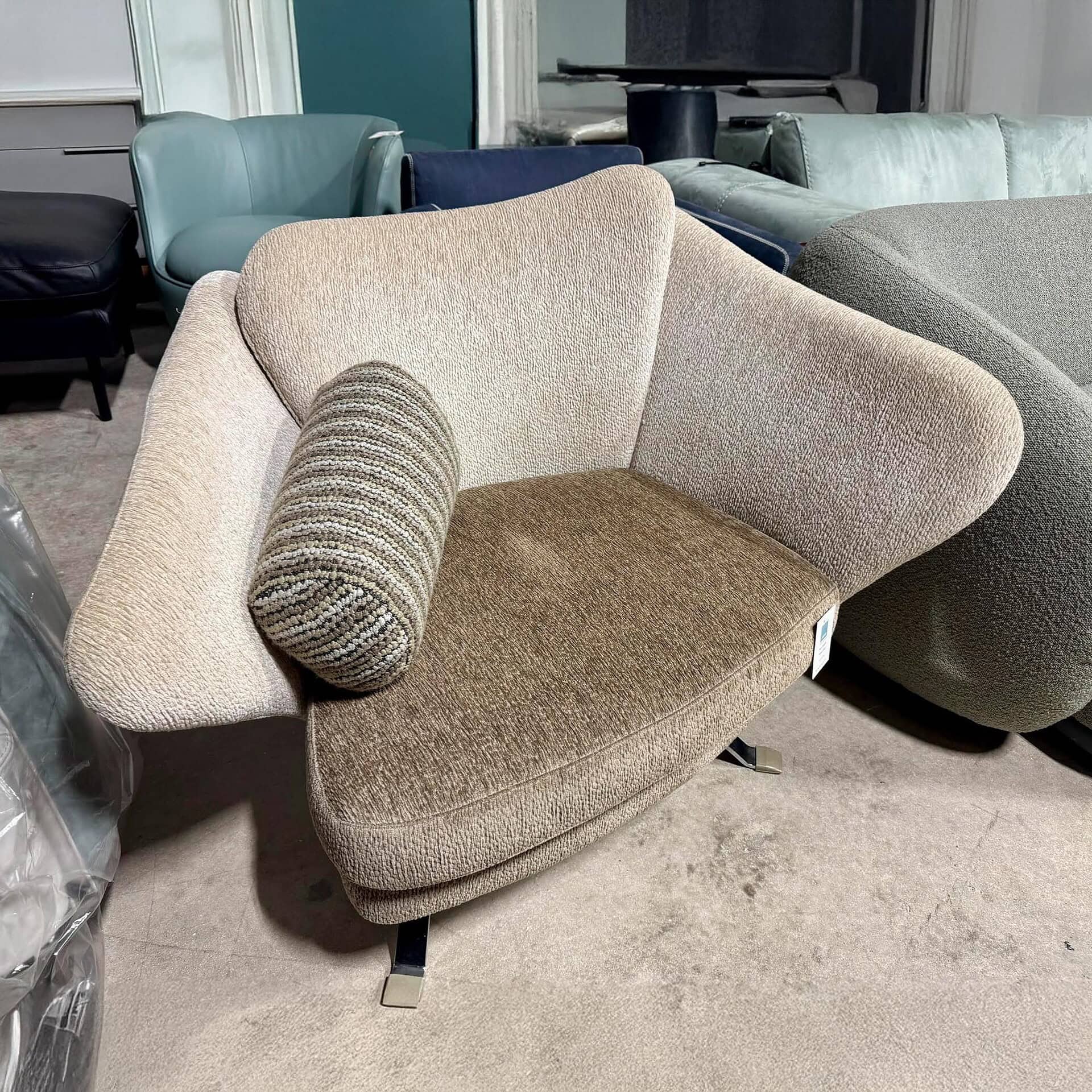 Stylish beige and brown upholstered armchair with unique curved design, perfect for contemporary living spaces.
