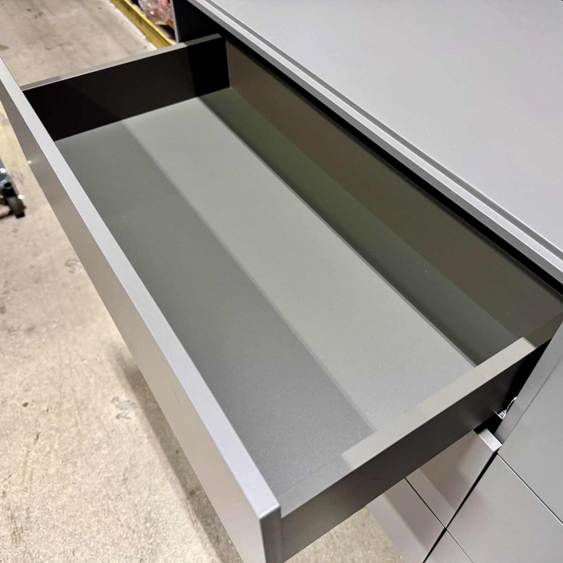 Close-up of a contemporary gray kitchen drawer with smooth interior and soft-close mechanism.