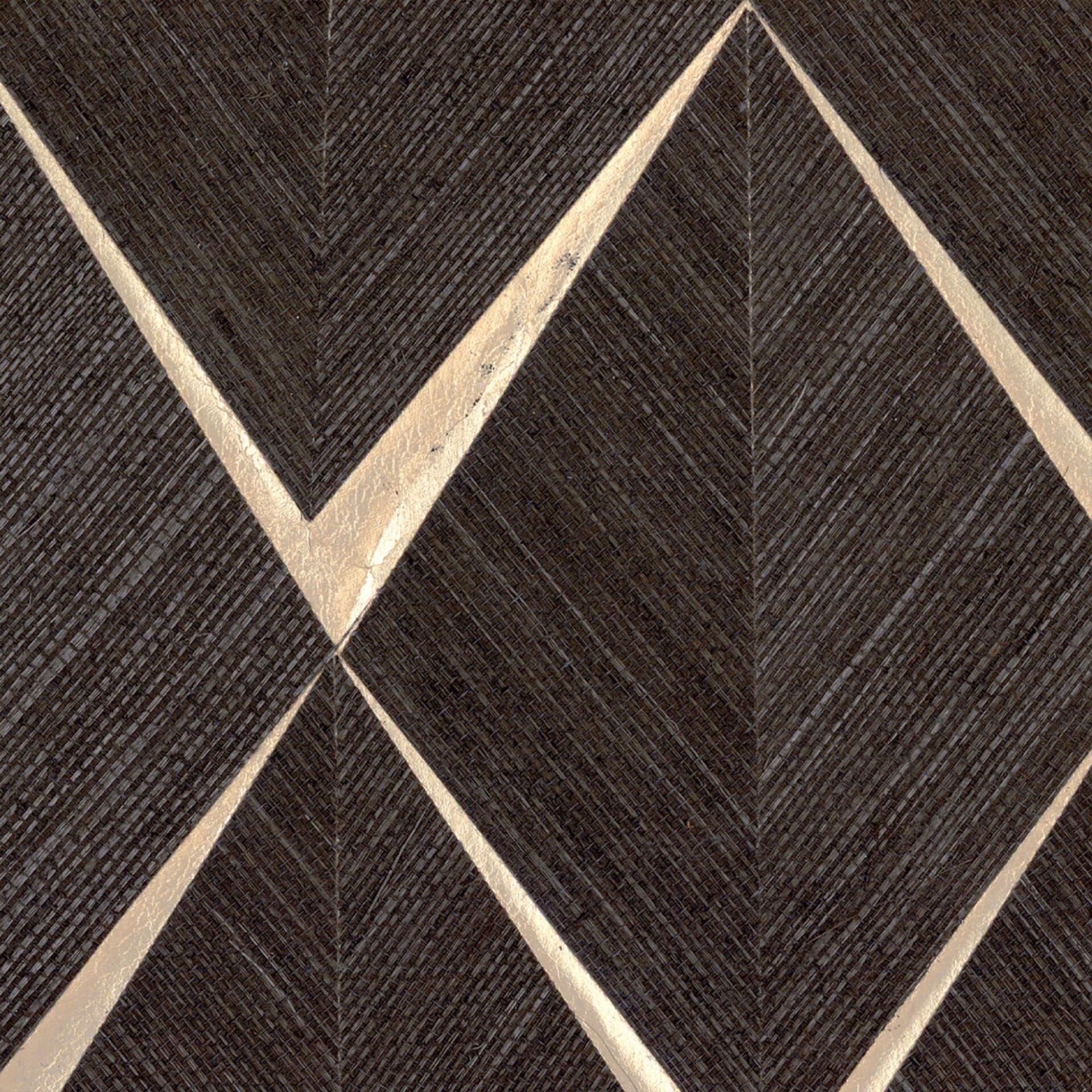 A close-up of a dark, textured background with a woven pattern, featuring bold, shimmering gold chevron lines creating a geometric design.