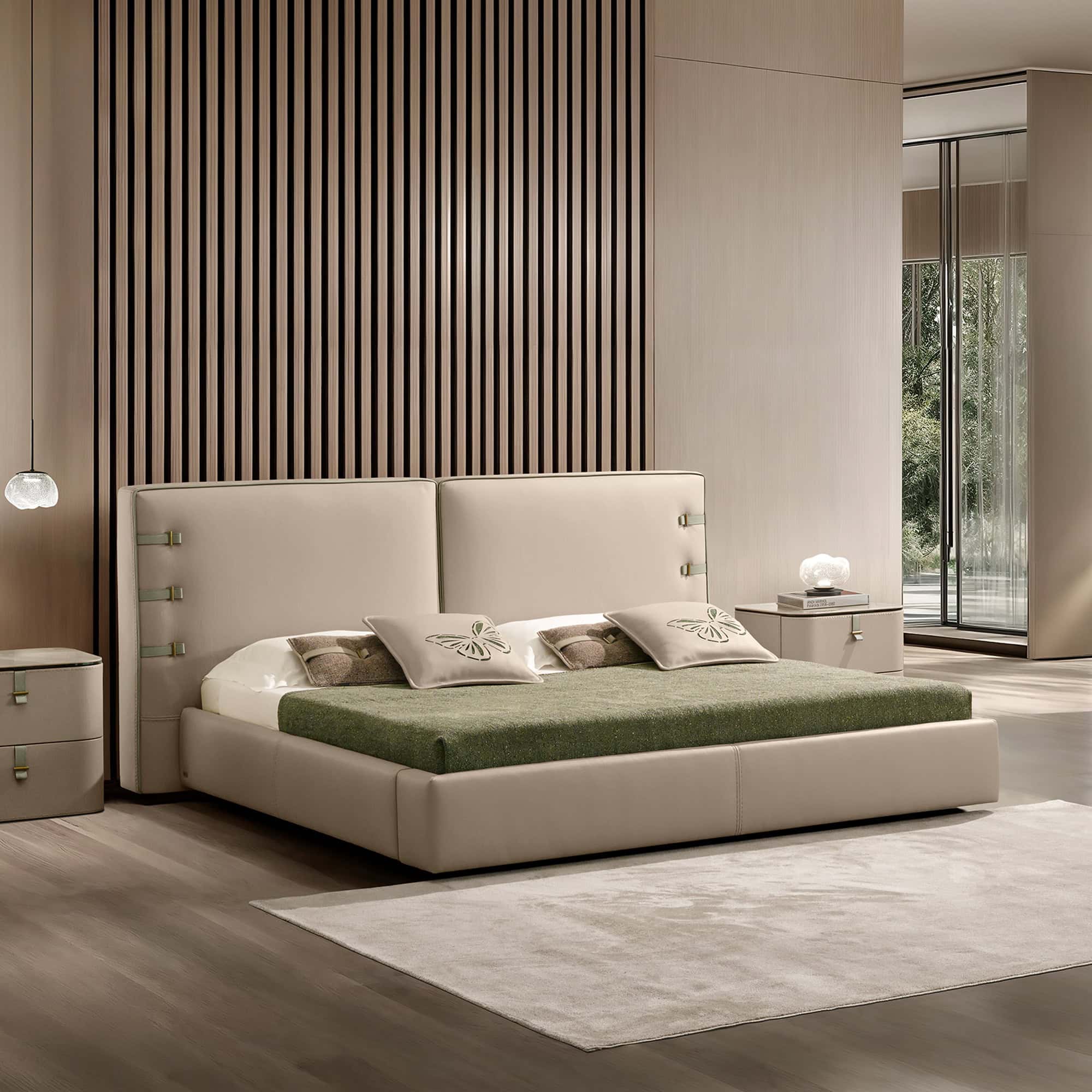 A modern bedroom with a beige upholstered bed, green blanket, and butterfly pillows. A slatted wooden accent wall is behind the bed, and a large window shows green trees. Beige nightstands with lamps flank the bed.
