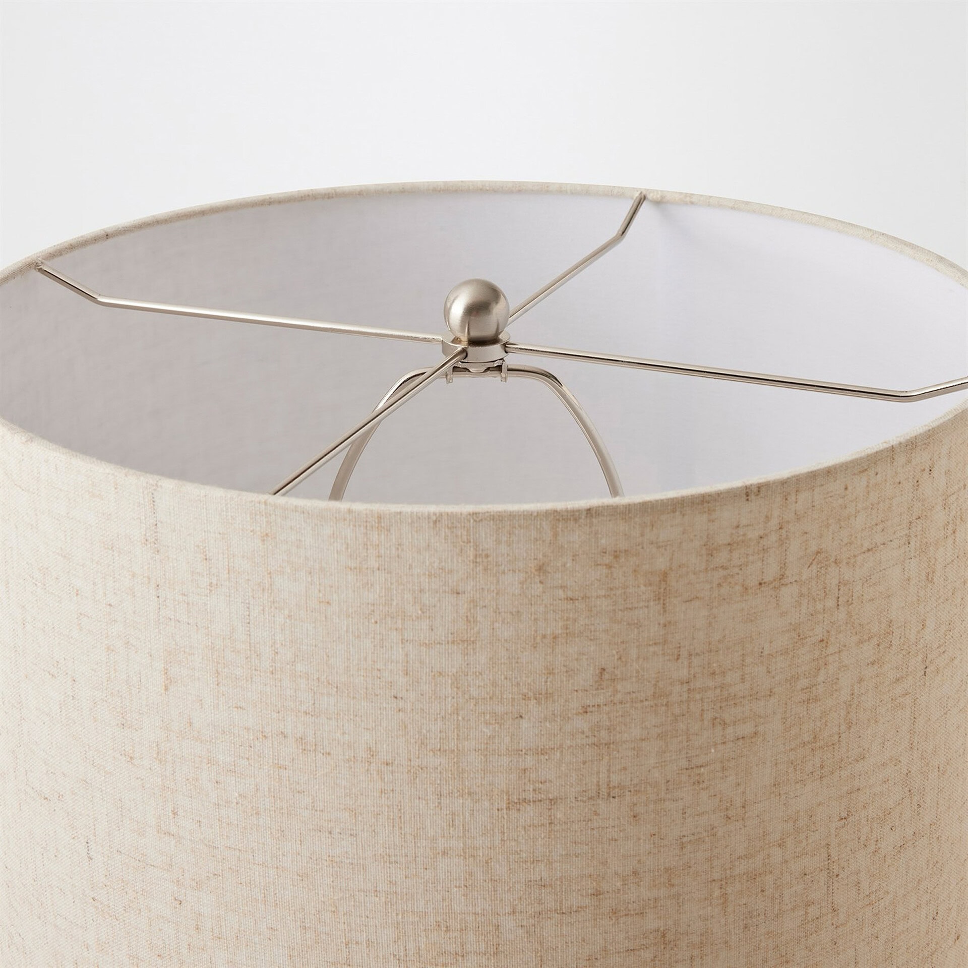 Top-down view of a cylindrical lampshade with a textured light beige fabric exterior and white interior, featuring a brushed nickel spider fitter.