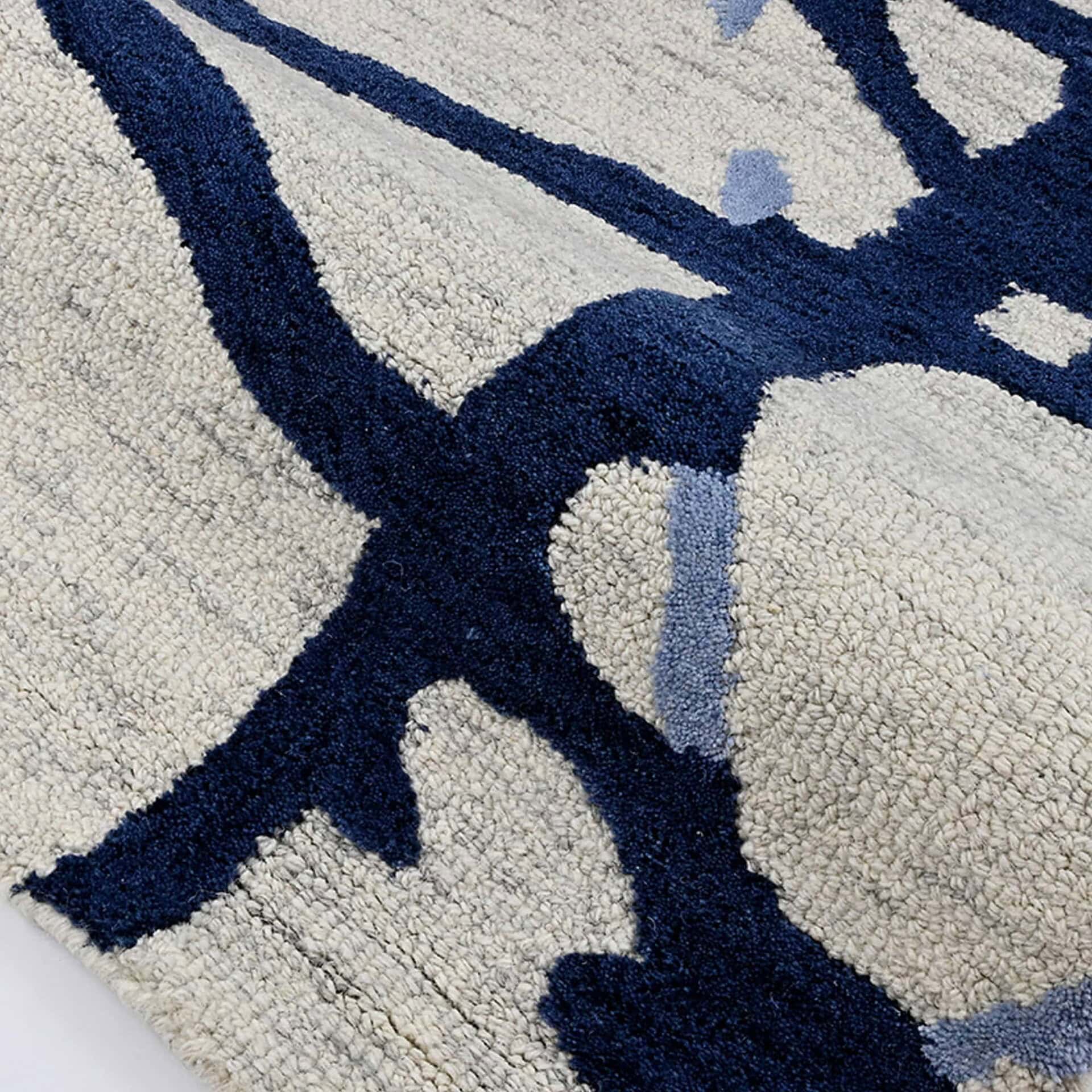 Close-up of a textured rug with an abstract pattern in deep navy blue, light beige, and sky blue.