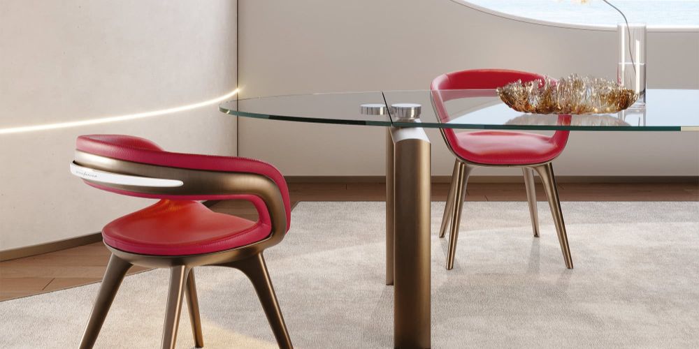 Two modern red chairs with bronze frames and white accents are arranged around a glass-top table on a light rug. A glowing light strip is embedded in the beige wall. Nido Wood Dining Chair by Reflex