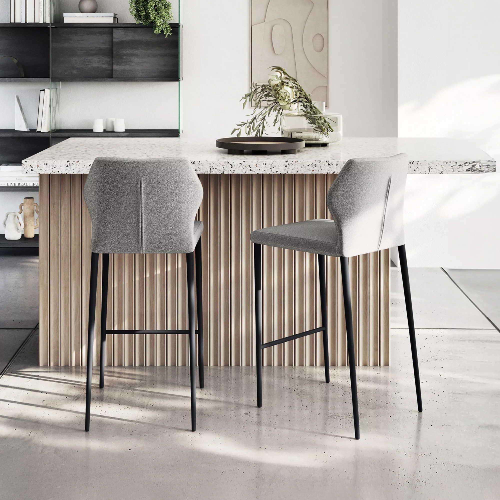 Two grey bar stools with black legs in front of a kitchen island with a terrazzo top and fluted wood base in a modern, minimalist room.