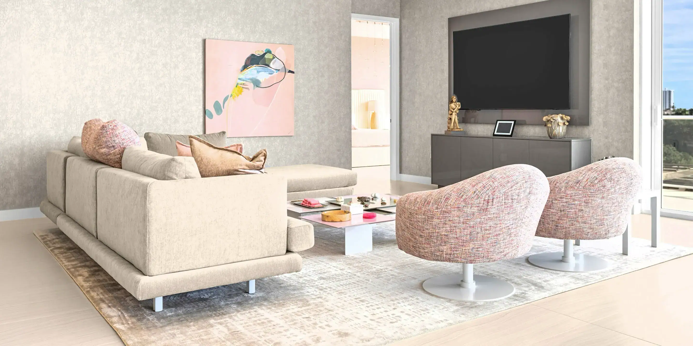 Contemporary condo living room featuring cozy armchairs, a coffee table, and expansive city views th.