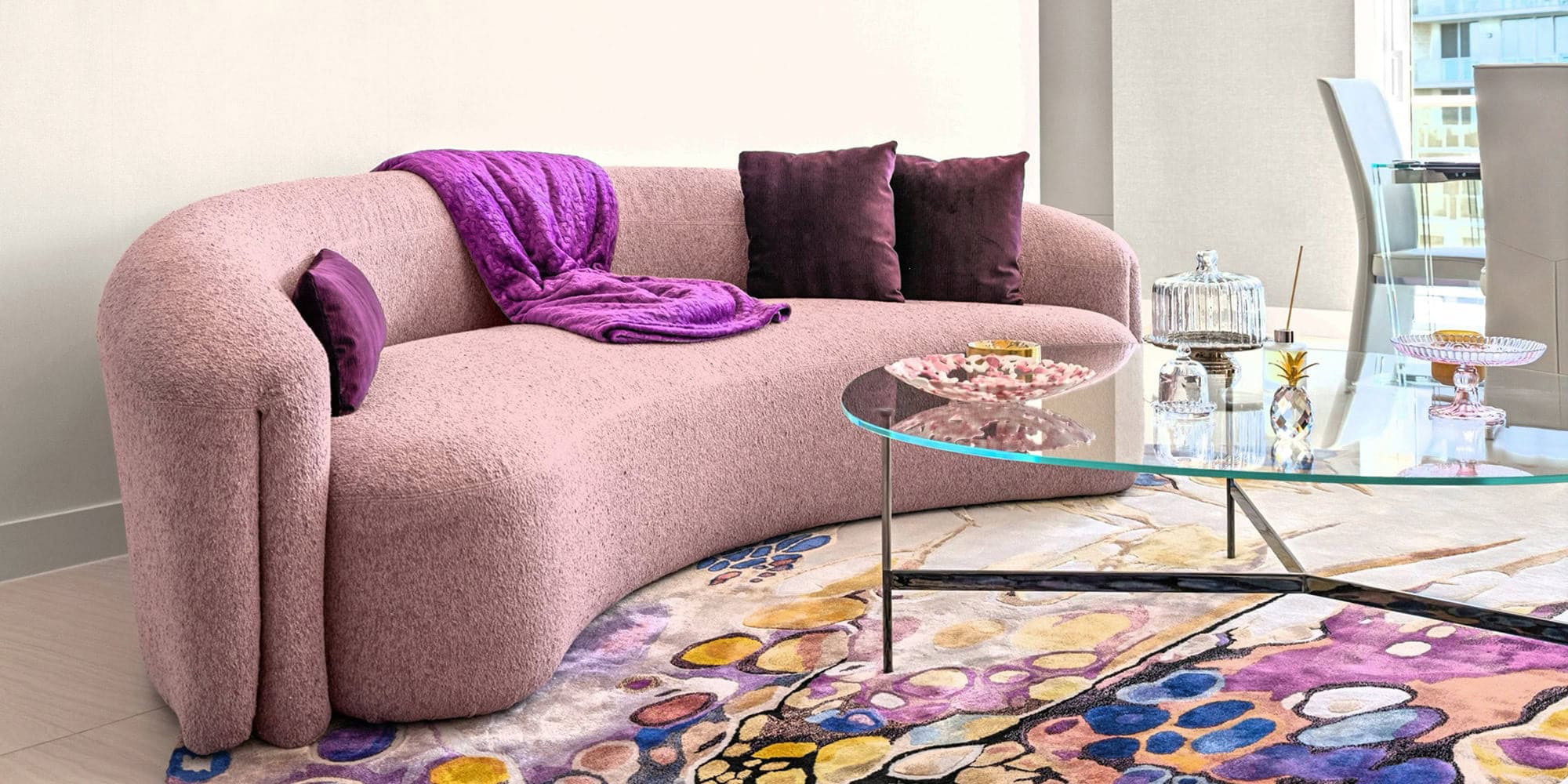 Modern Pink Sofa with Purple Accents in a Stylish Condo Elegant pink sofa with purple cushions and throw in a contemporary condo living room.