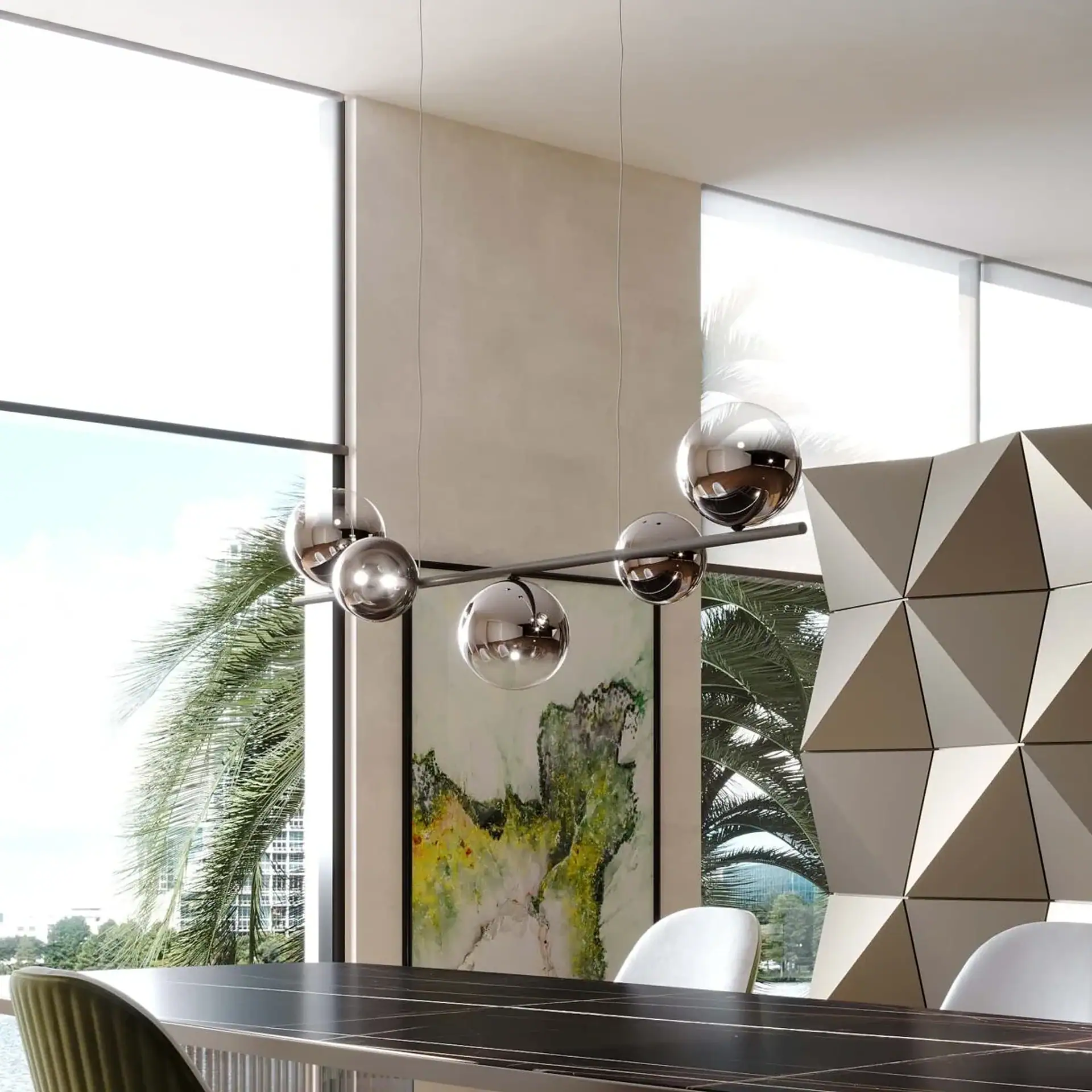 A modern dining room with a chrome spherical chandelier, a dark table, and large windows overlooking palm trees and water. An abstract painting and geometric wall panel are also visible.