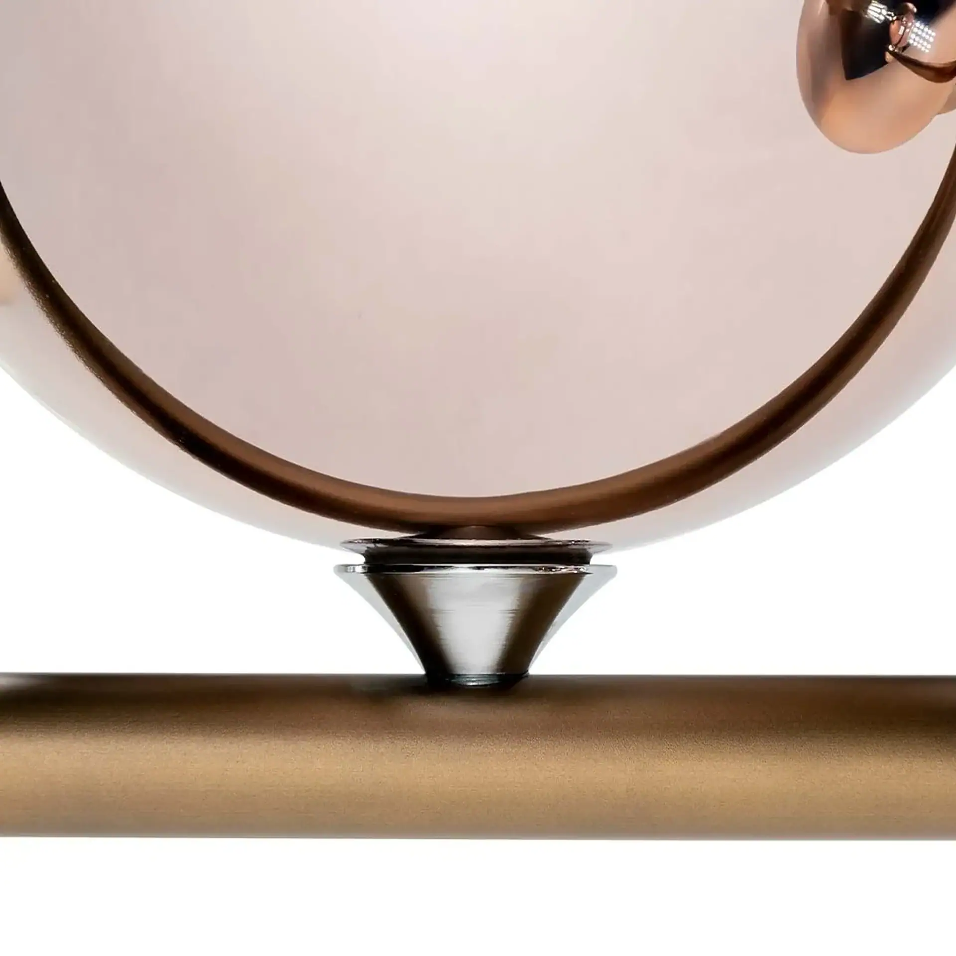 Close-up of a rose gold sphere resting on a silver conical support, which sits on a bronze cylindrical bar, all against a white background.