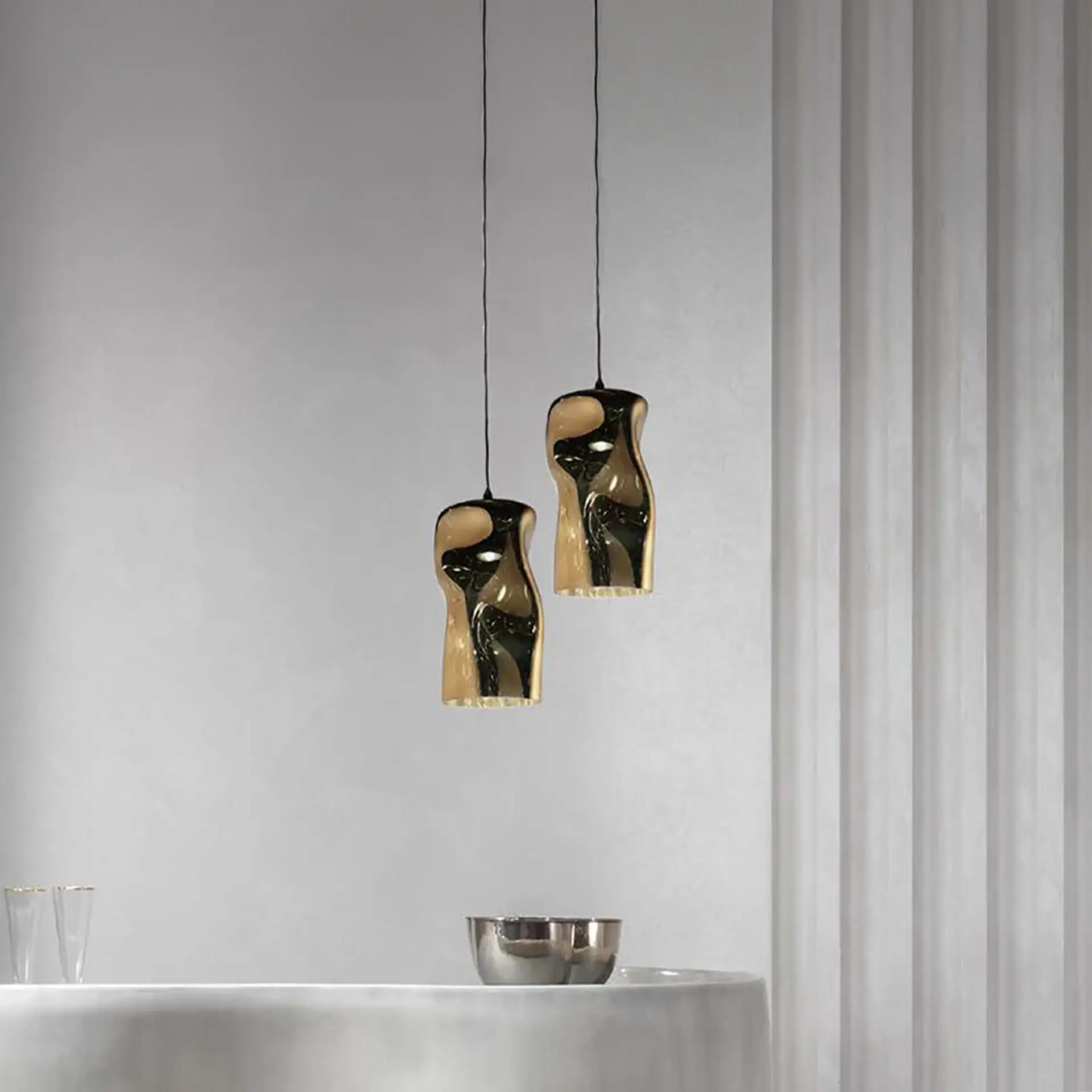 Modern Dandolo pendant lamps with reflective gold finish in minimalist interior.