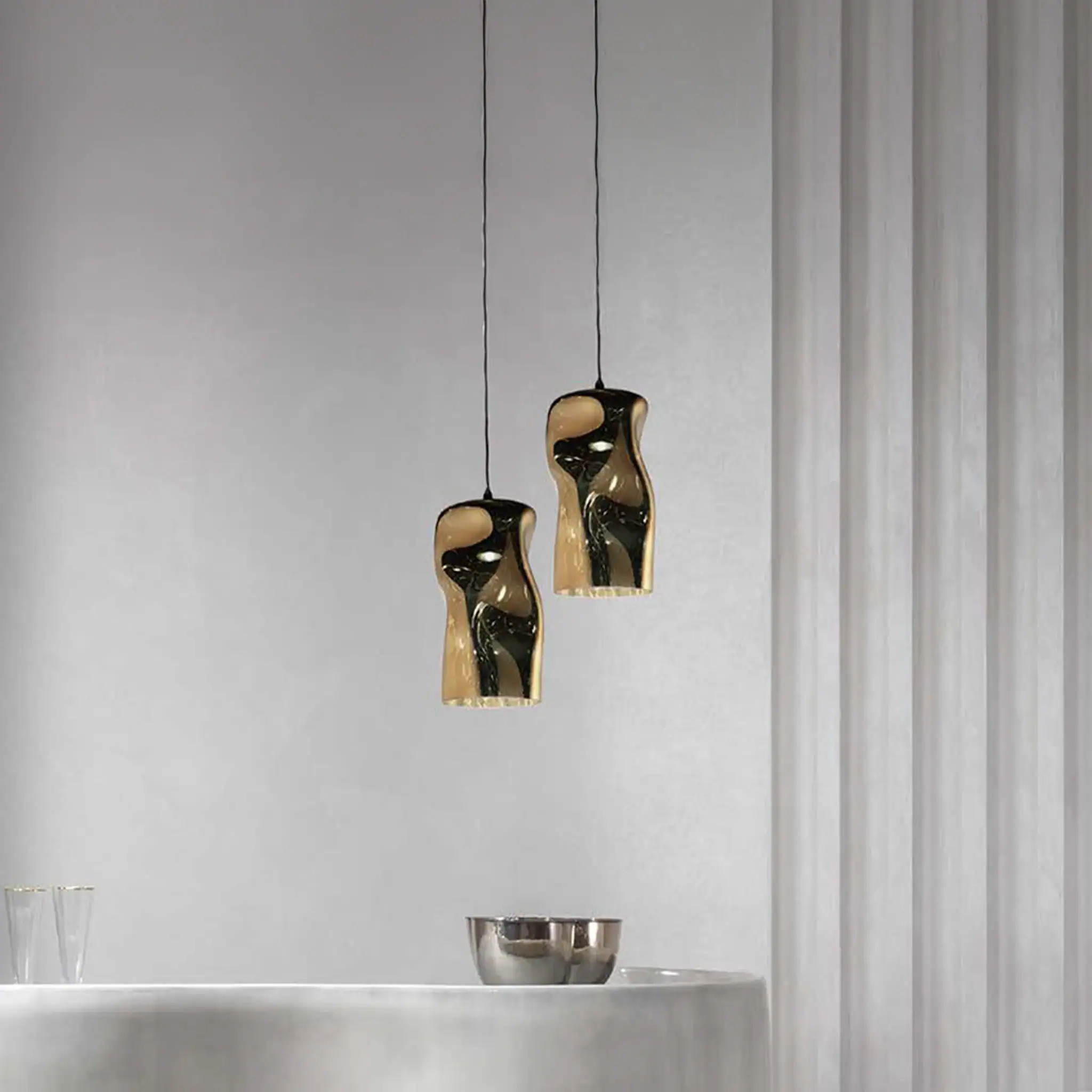 Modern Dandolo pendant lamps with reflective gold finish in minimalist interior.