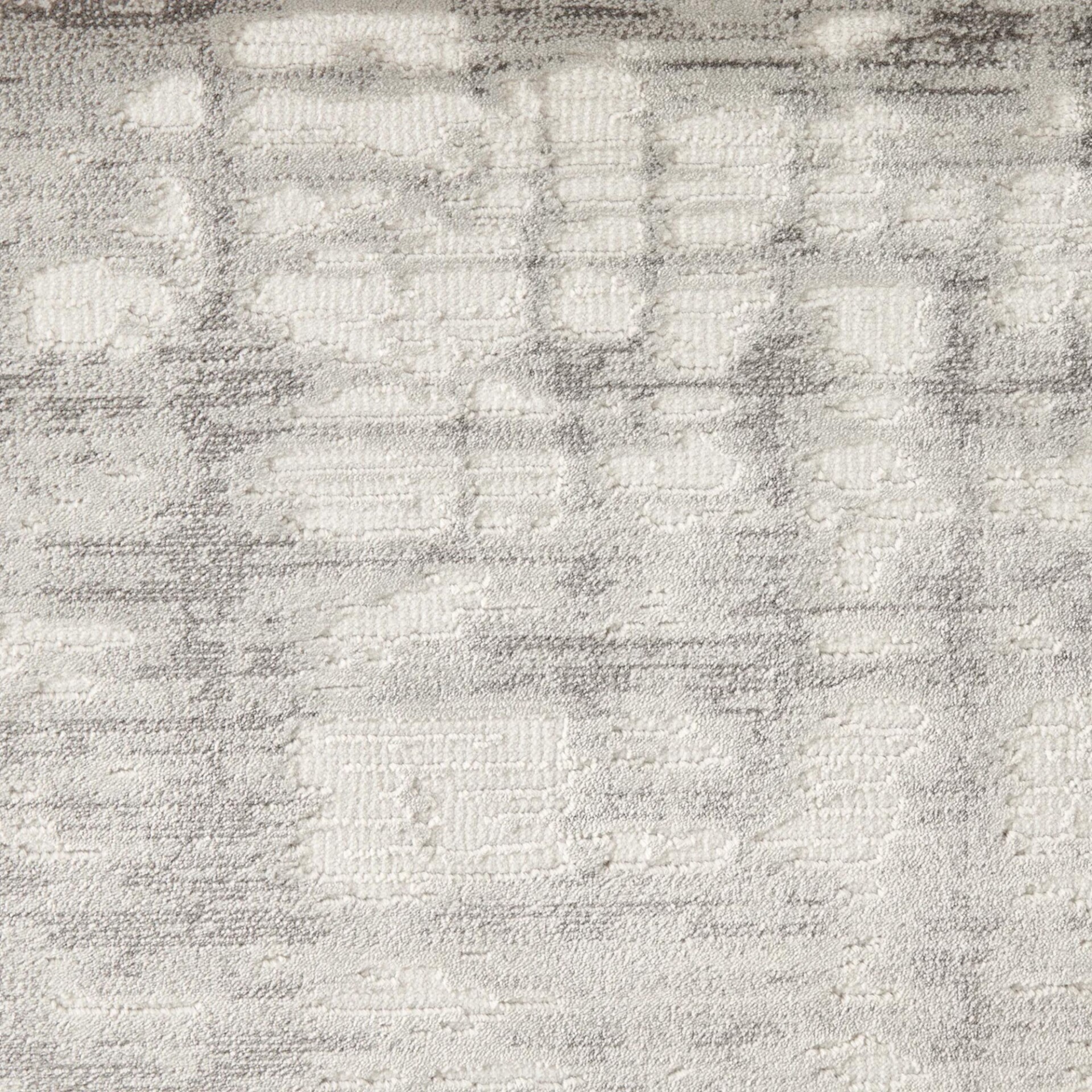 Close-up of a textured rug with an abstract, distressed grid pattern in off-white and grey.
