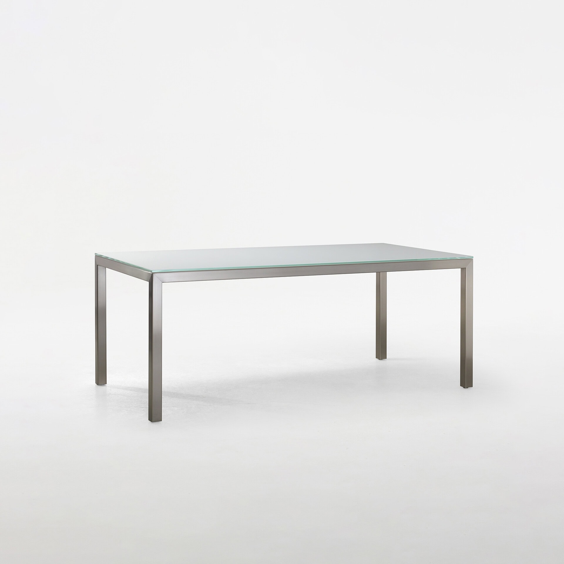 Sleek glass dining table with stainless steel frame, perfect for modern homes and dining spaces.