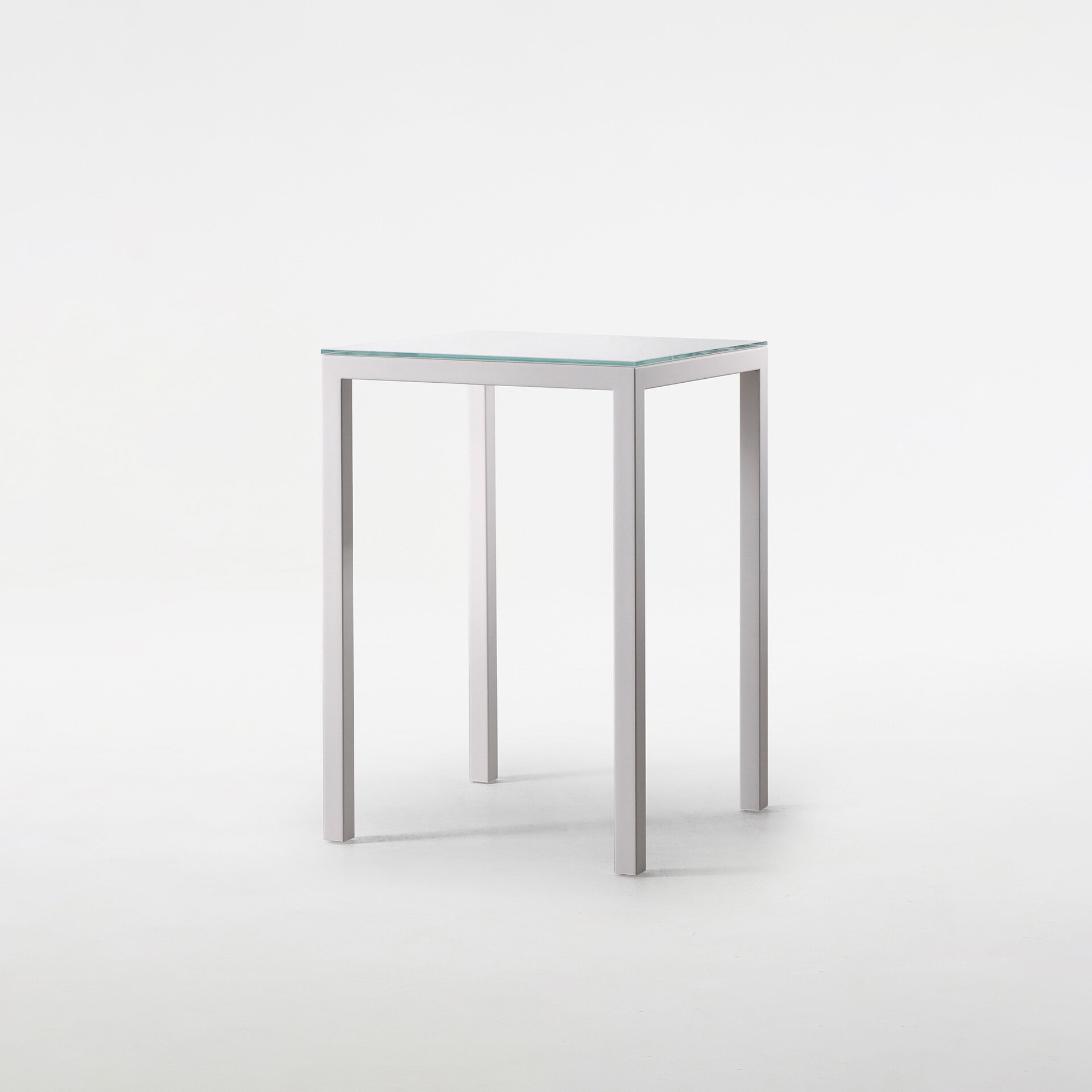 Contemporary glass top side table with sleek metal legs for modern interiors.
