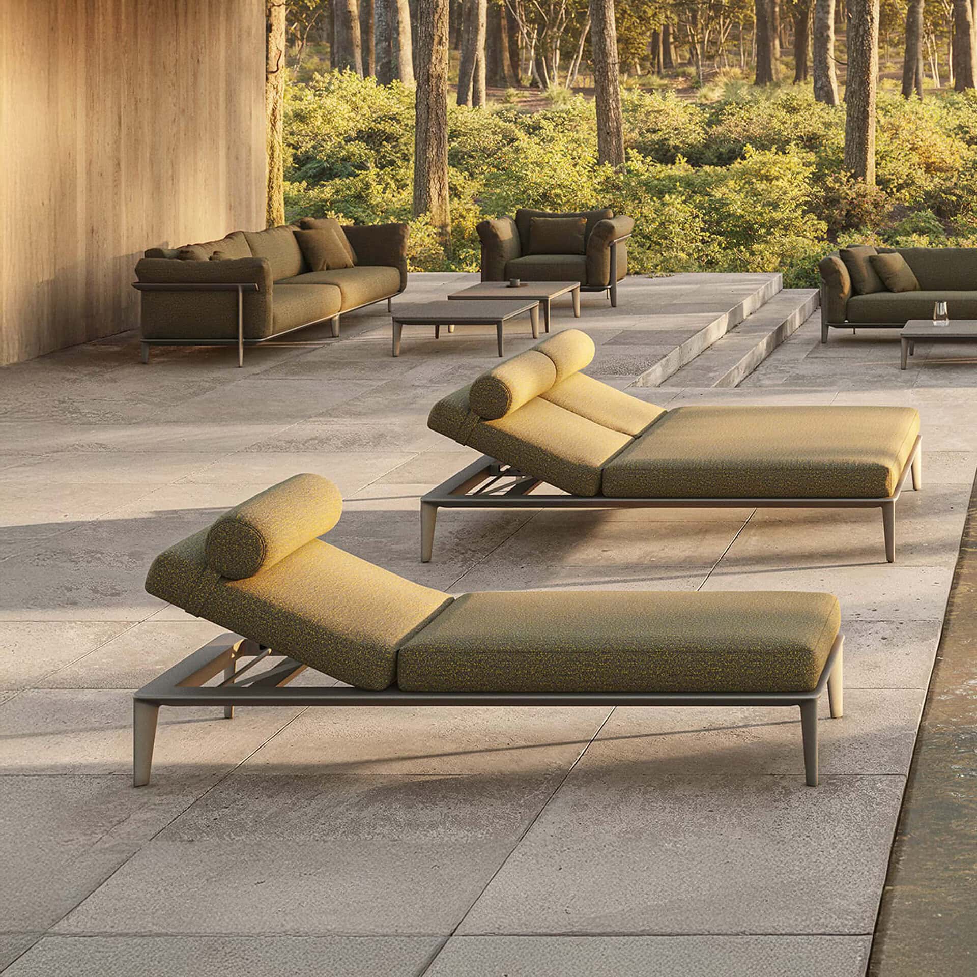 Modern outdoor furniture set with lounge beds and seating in a natural setting.