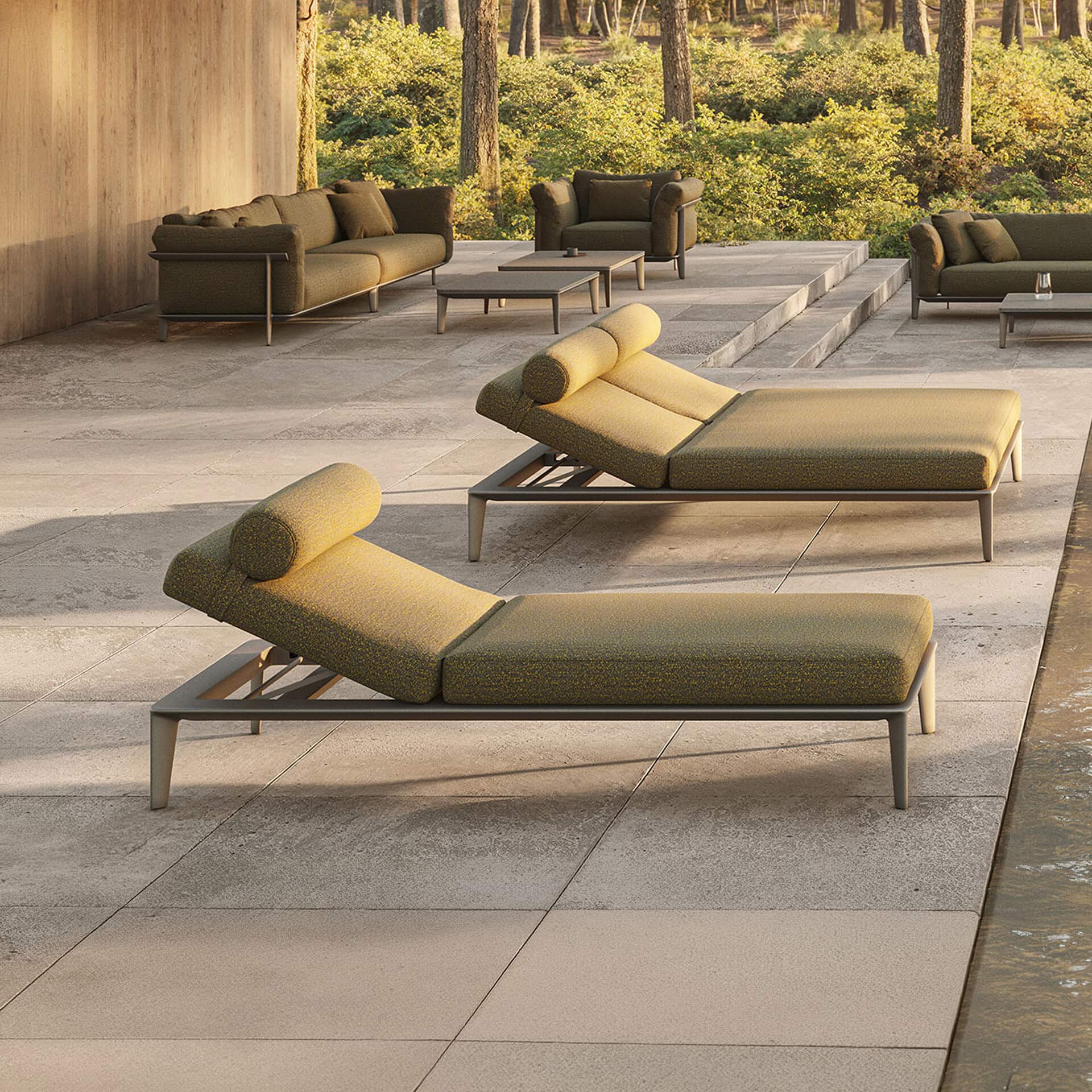 Modern outdoor furniture set with lounge beds and seating in a natural setting.