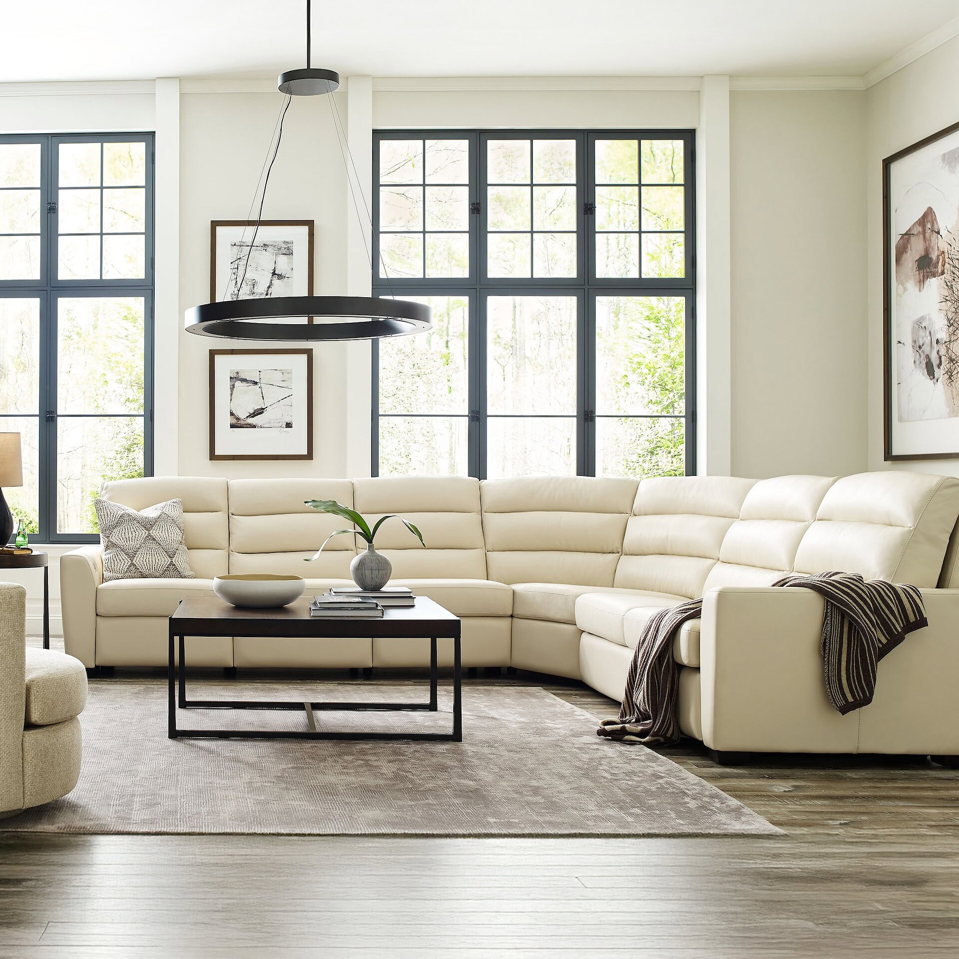 Elegant white sectional sofa in a bright, airy living room with large windows and modern decor.