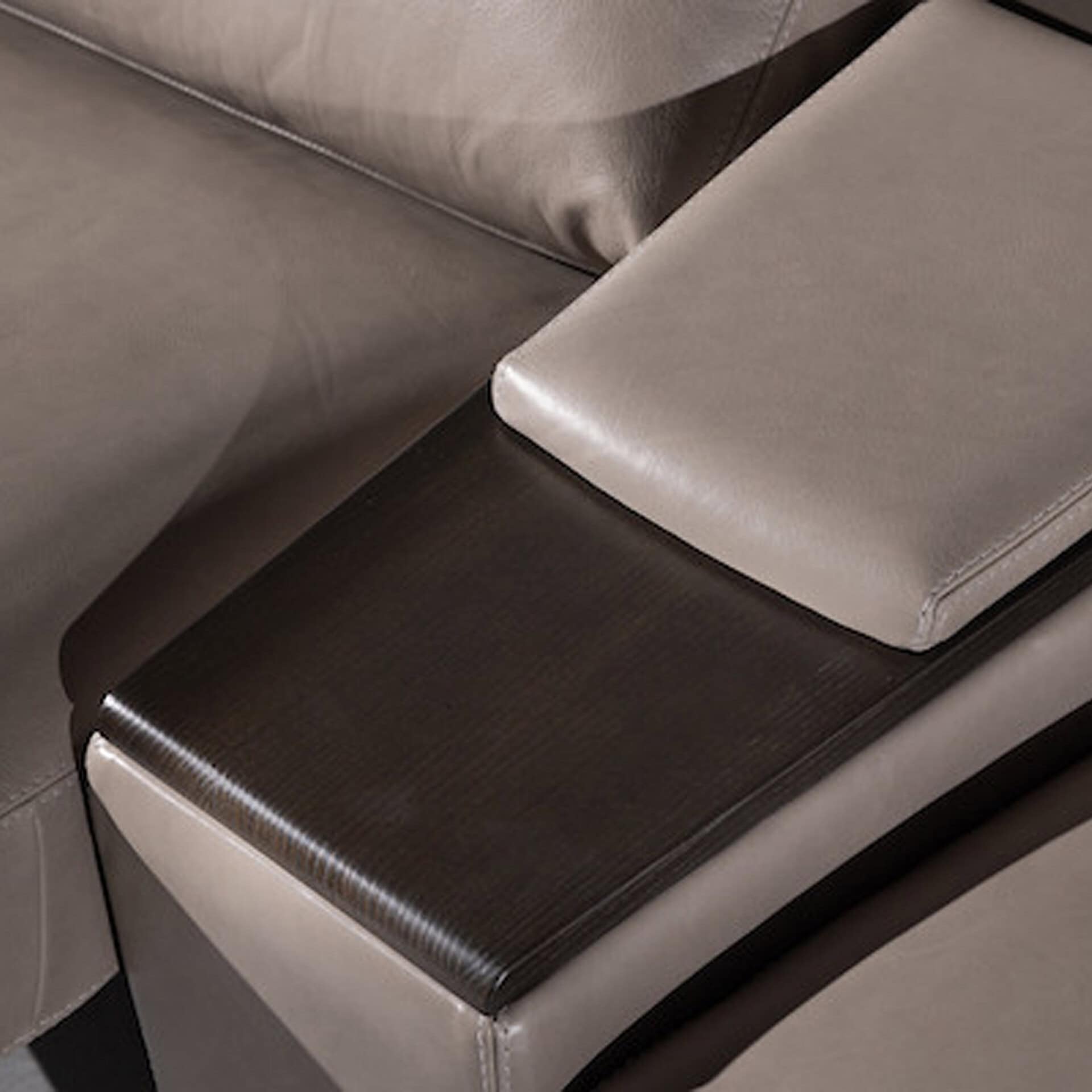 Close-up of a sleek leather armrest and corner of a modern sofa.