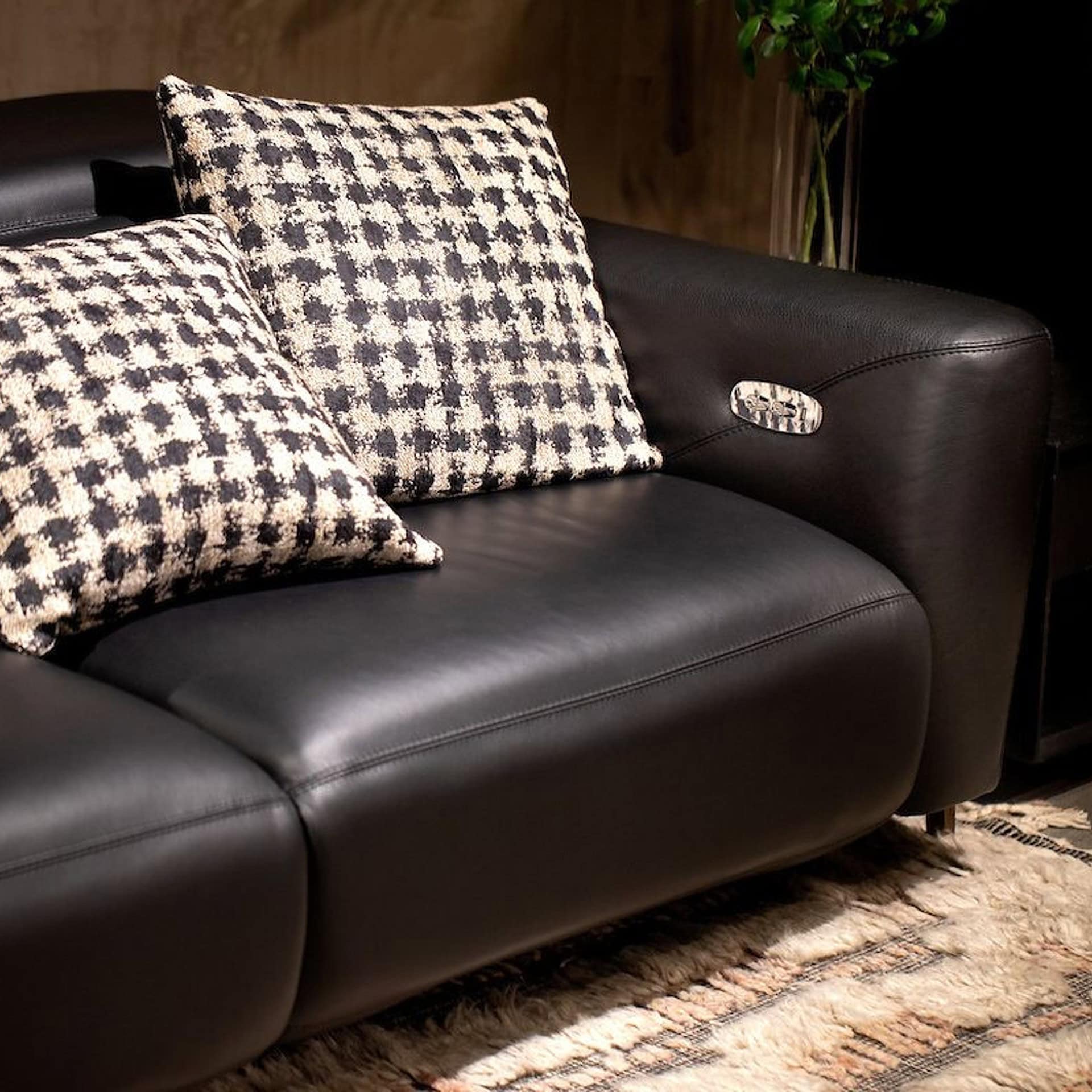 Black leather sofa with houndstooth pillows, perfect for contemporary living rooms.