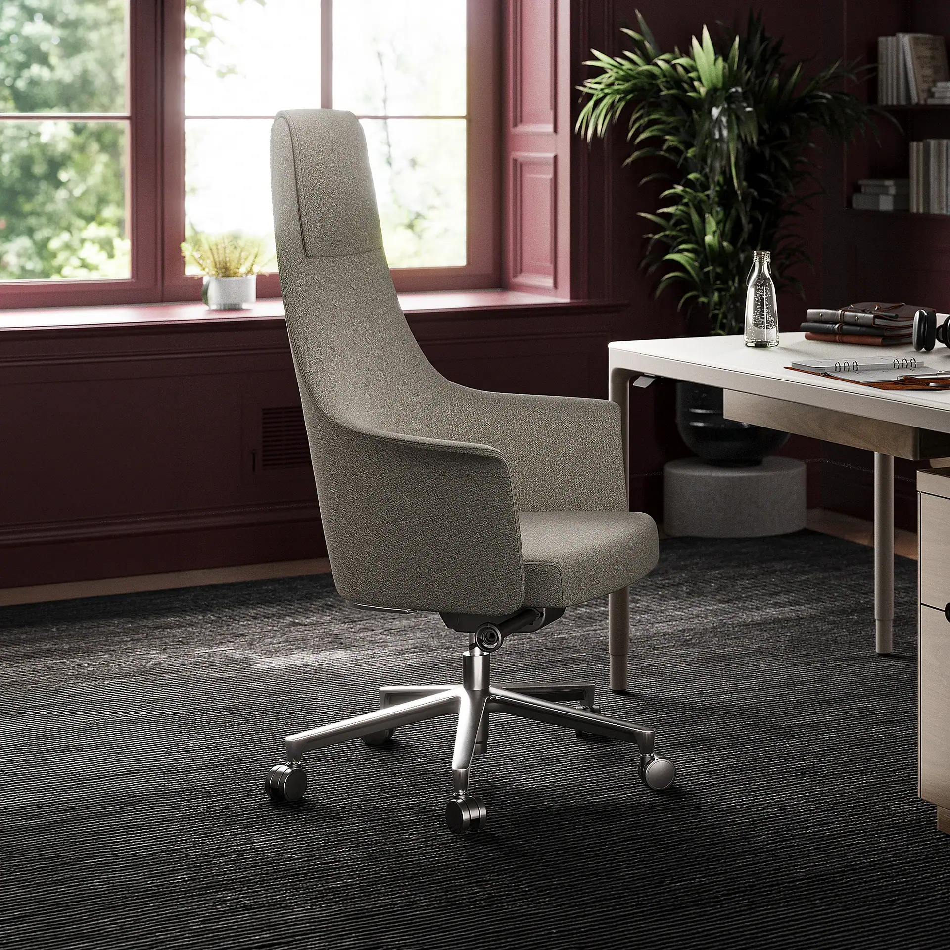 A gray high-backed office chair in a modern office room with a white desk, a large window, and dark red walls.