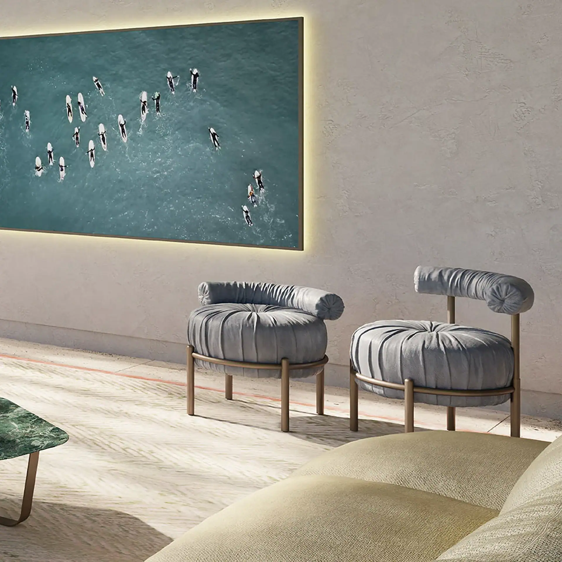 A modern living room with a large, backlit screen displaying an aerial view of surfers in blue water. Two gray pleated armchairs and a green marble table are visible.