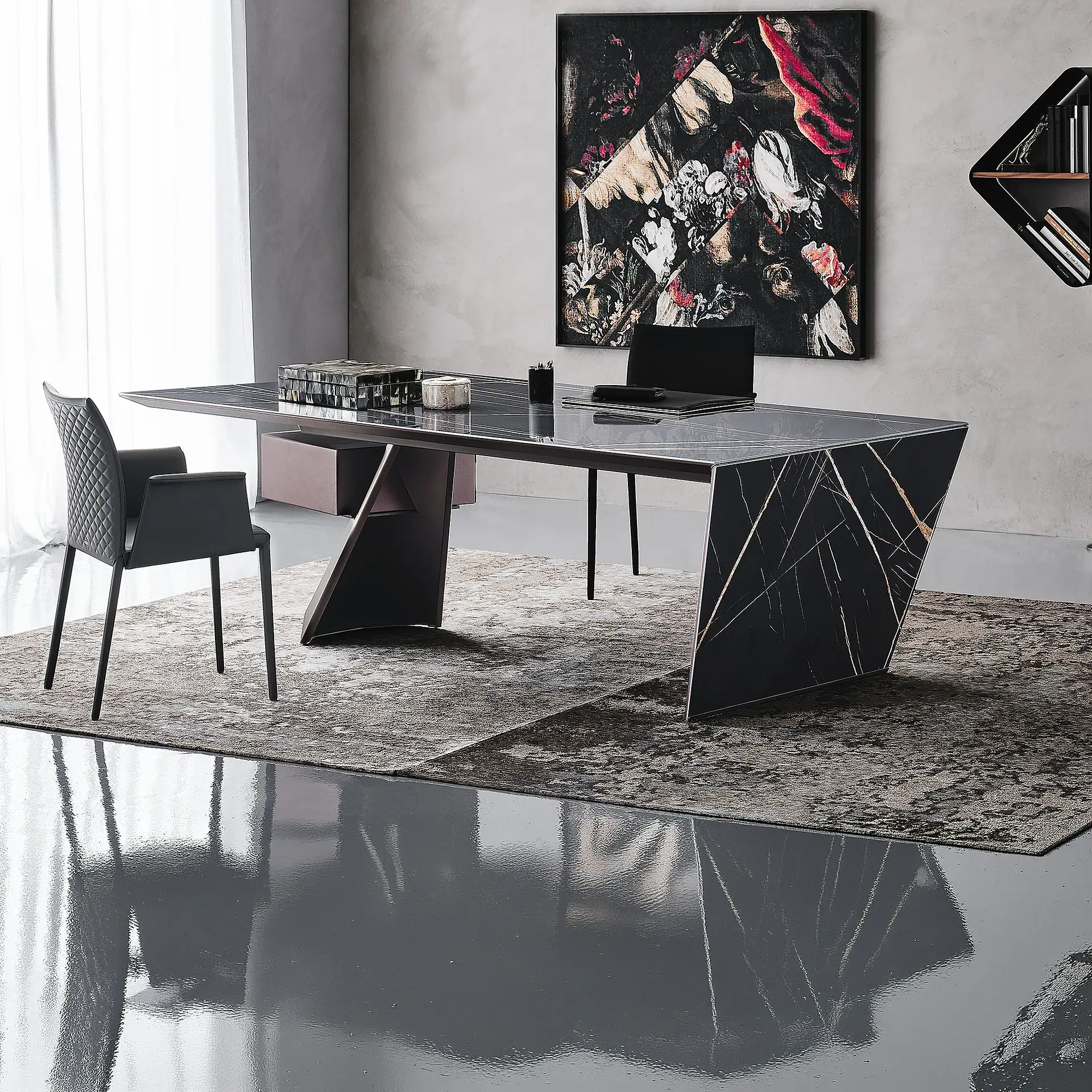 A modern home office with a black marble desk, a black upholstered chair, abstract floral artwork, and a geometric wall shelf.