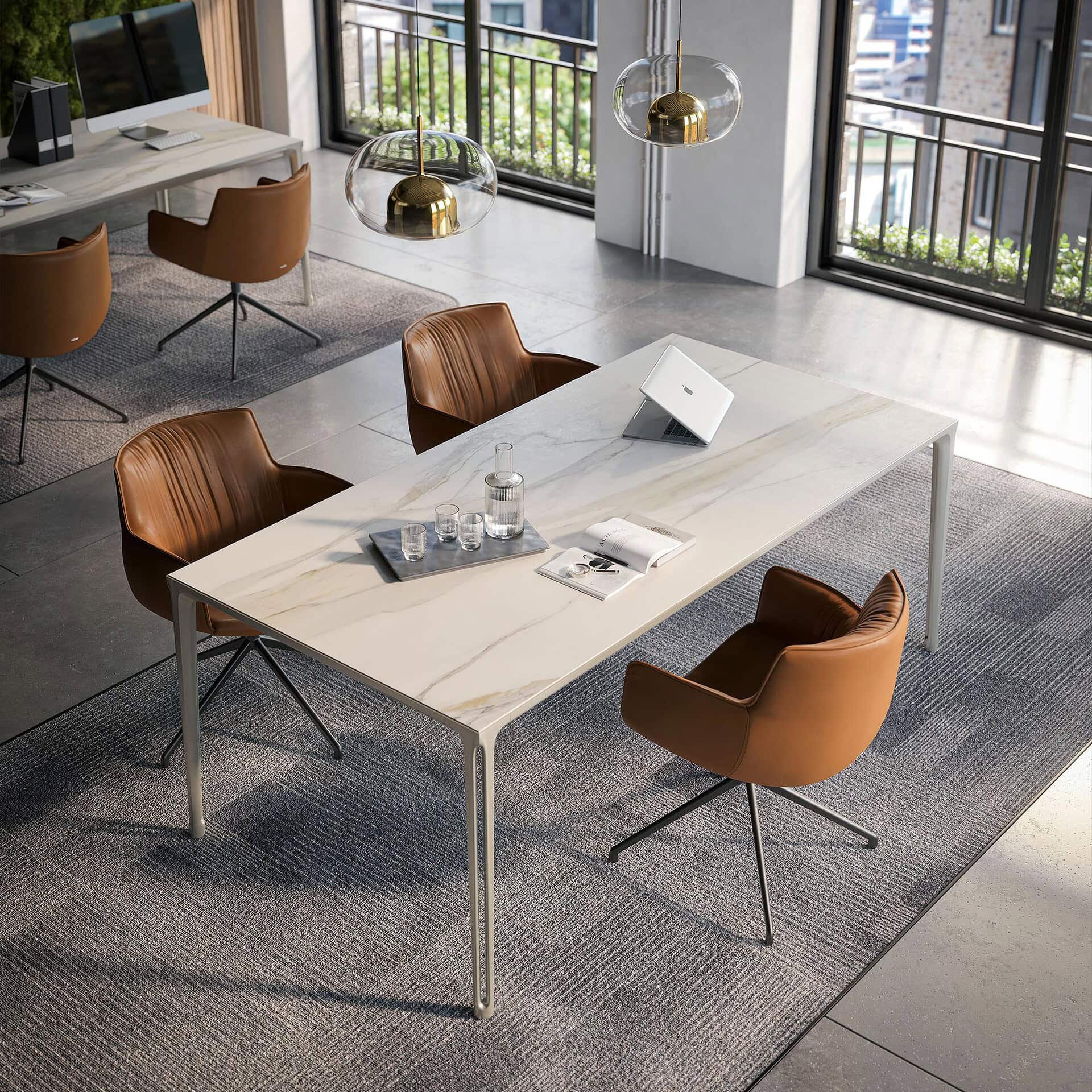A modern office meeting room with a long white marble table, brown leather chairs, large windows, and a green moss wall, featuring contemporary pendant lights and a laptop on the table.