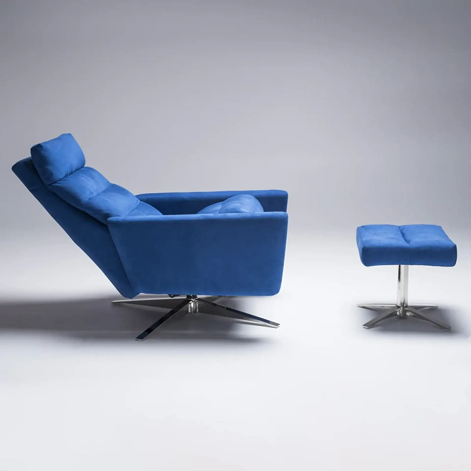 A royal blue recliner chair with a matching ottoman, both on silver star-shaped bases, against a light gray background.
