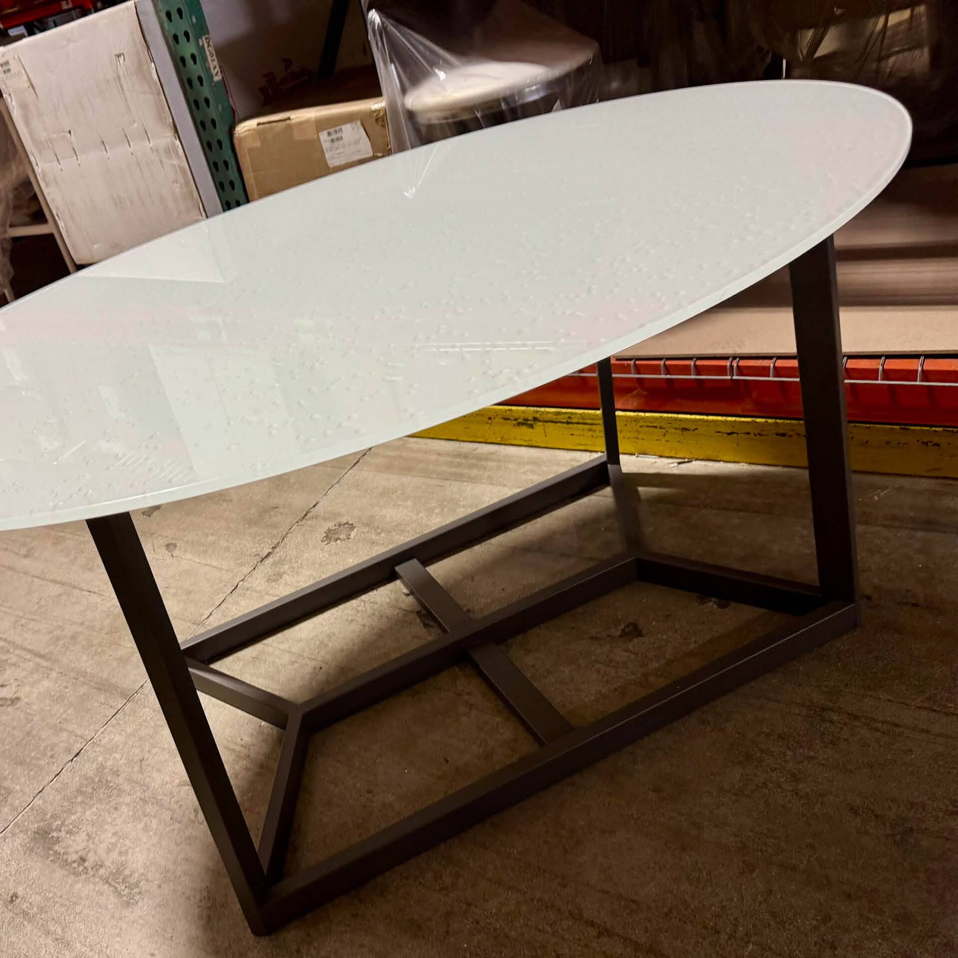 Oval dining table with a white tabletop and black metal frame. Perfect for contemporary dining space.
