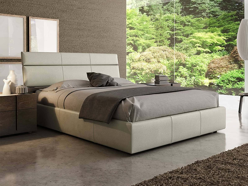 Modern leather bed in a stylish bedroom with large window overlooking lush greenery.