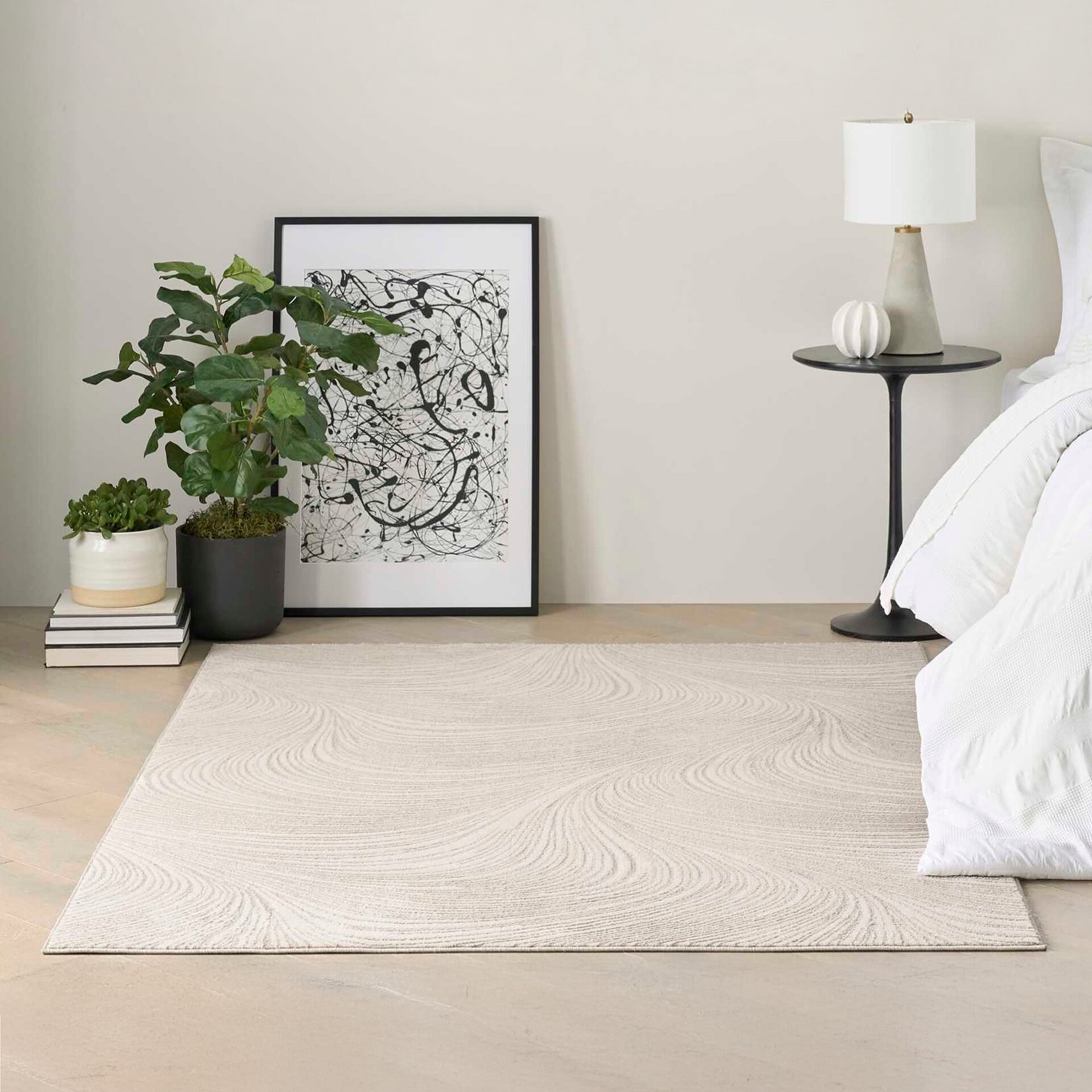 Elegant bedroom corner with plants, artwork, and a side table.