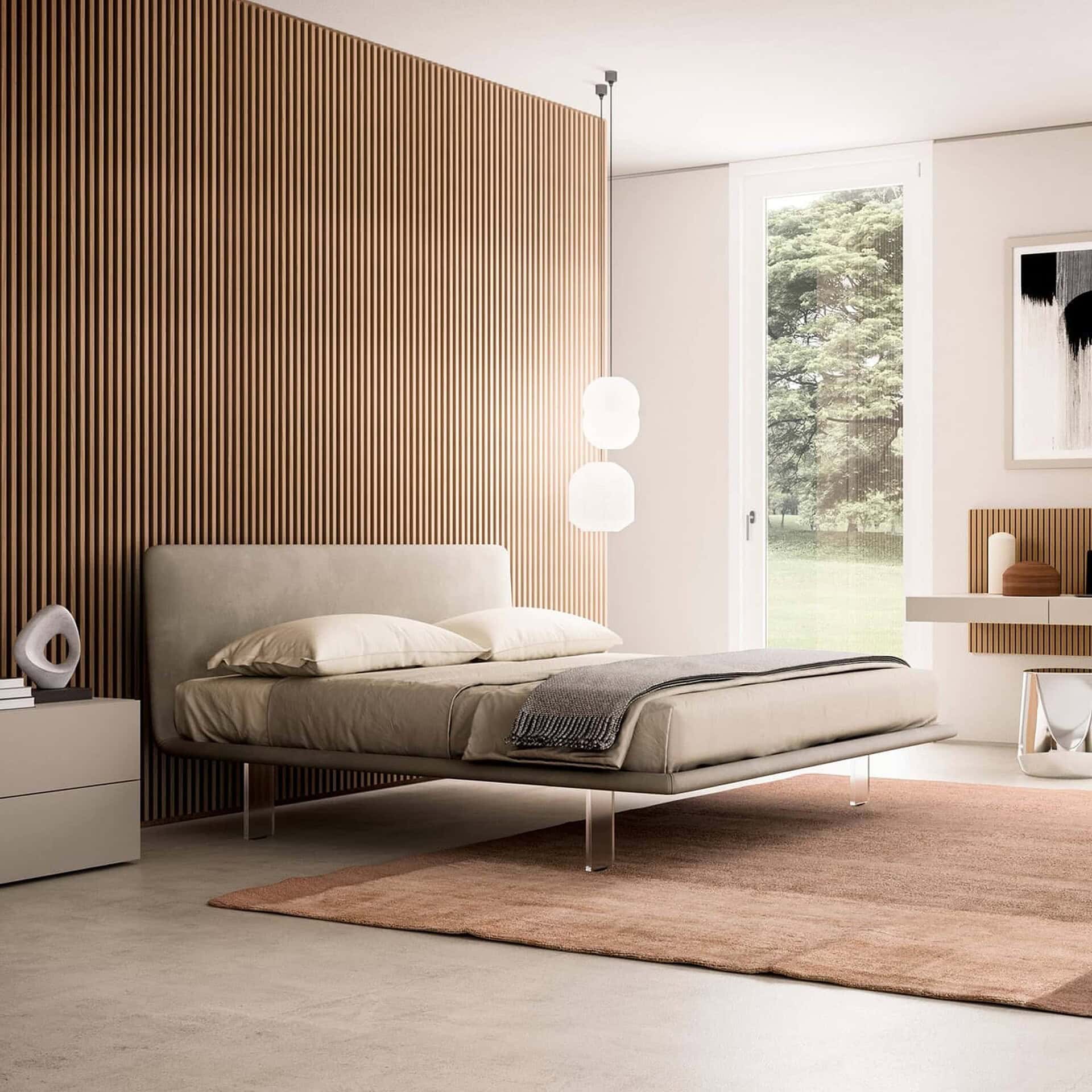 A modern bedroom with a light taupe floating bed, a vertical wood slat accent wall, and a large window overlooking green trees. A light grey nightstand and a floating console with decor are also visible.