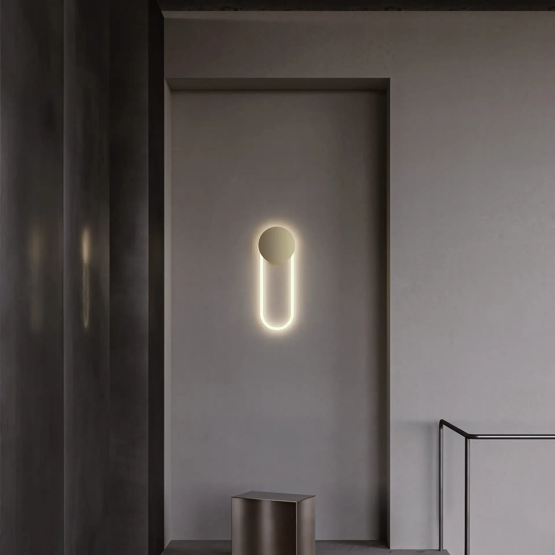 Modern wall sconce with circular and elongated design on a neutral wall.