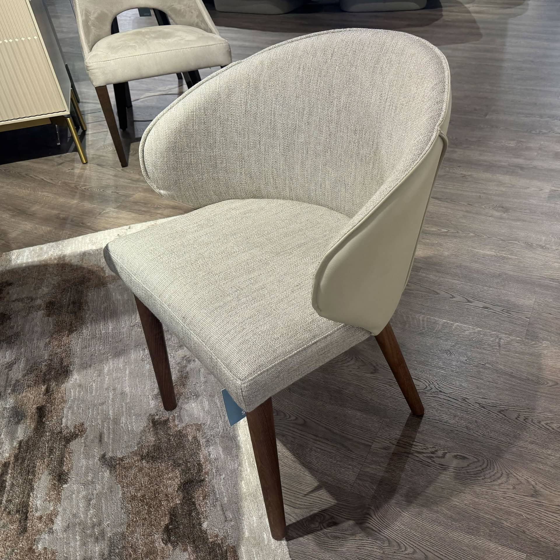 Upholstered Manta dining chair with wooden legs, perfect for modern dining rooms.