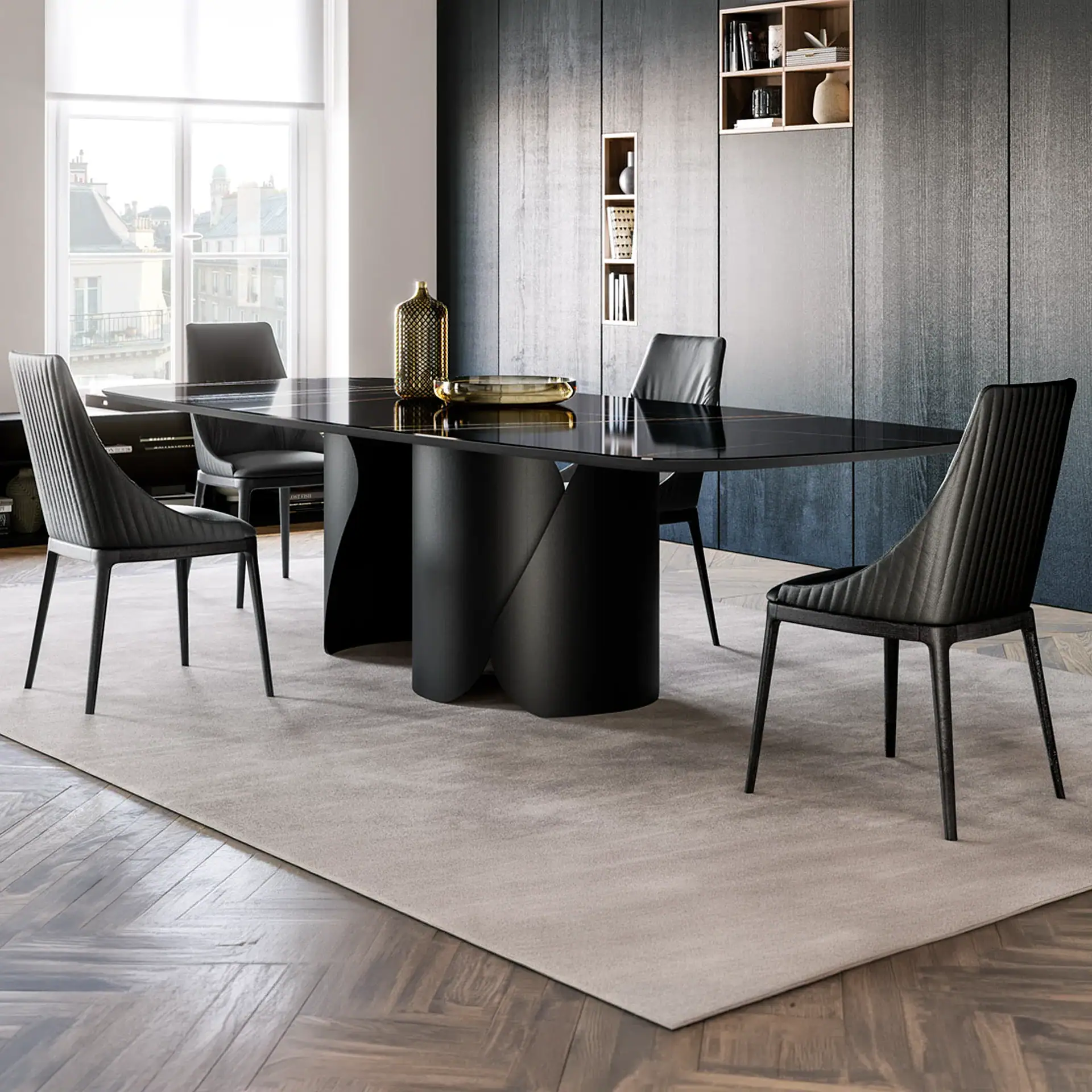 A modern dining room with a black rectangular table, four black chairs, a gold vase, and a gold tray on a light rug over a herringbone wood floor, next to a dark wood paneled wall with shelves and a large window.