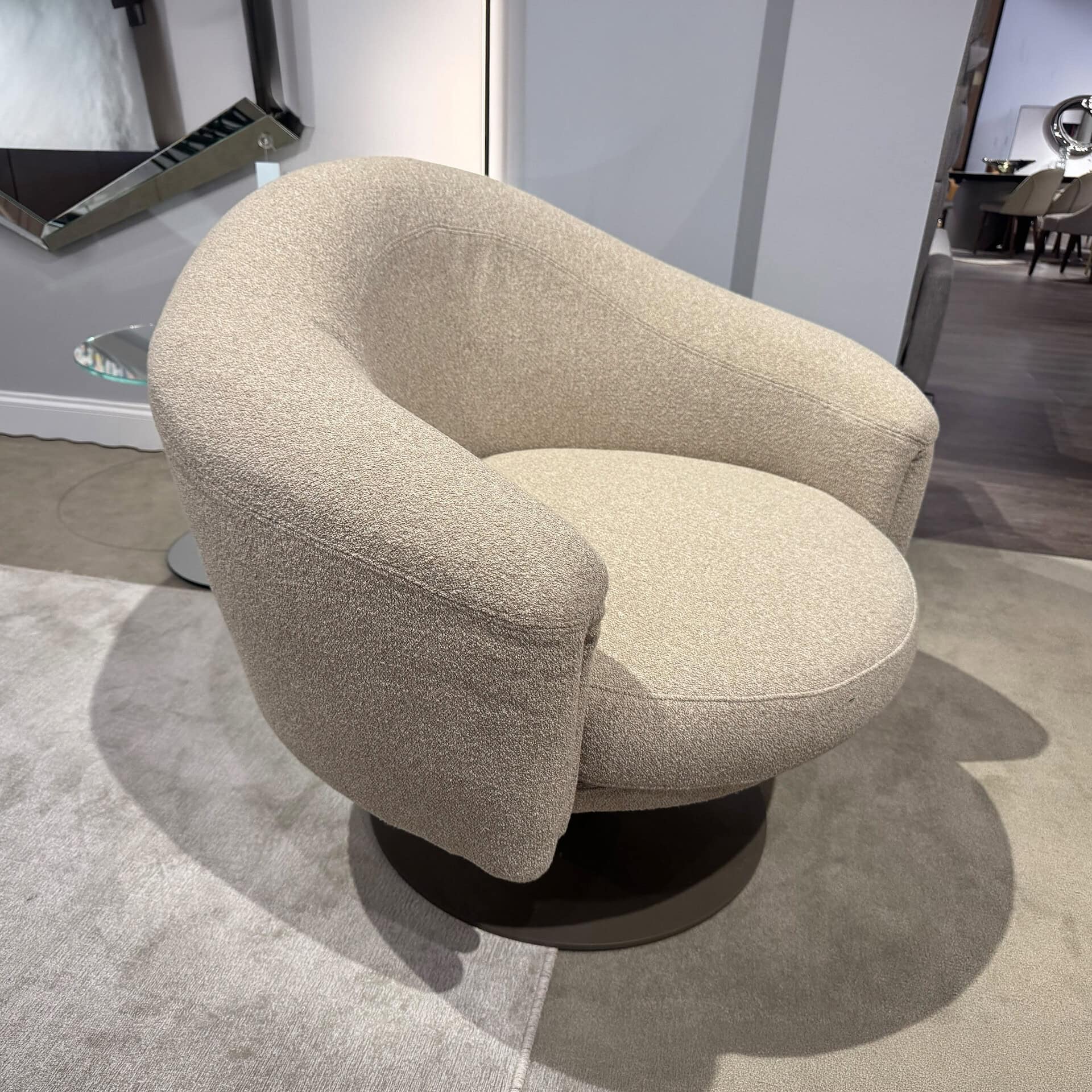 Modern beige upholstered swivel armchair with rounded back and seat.