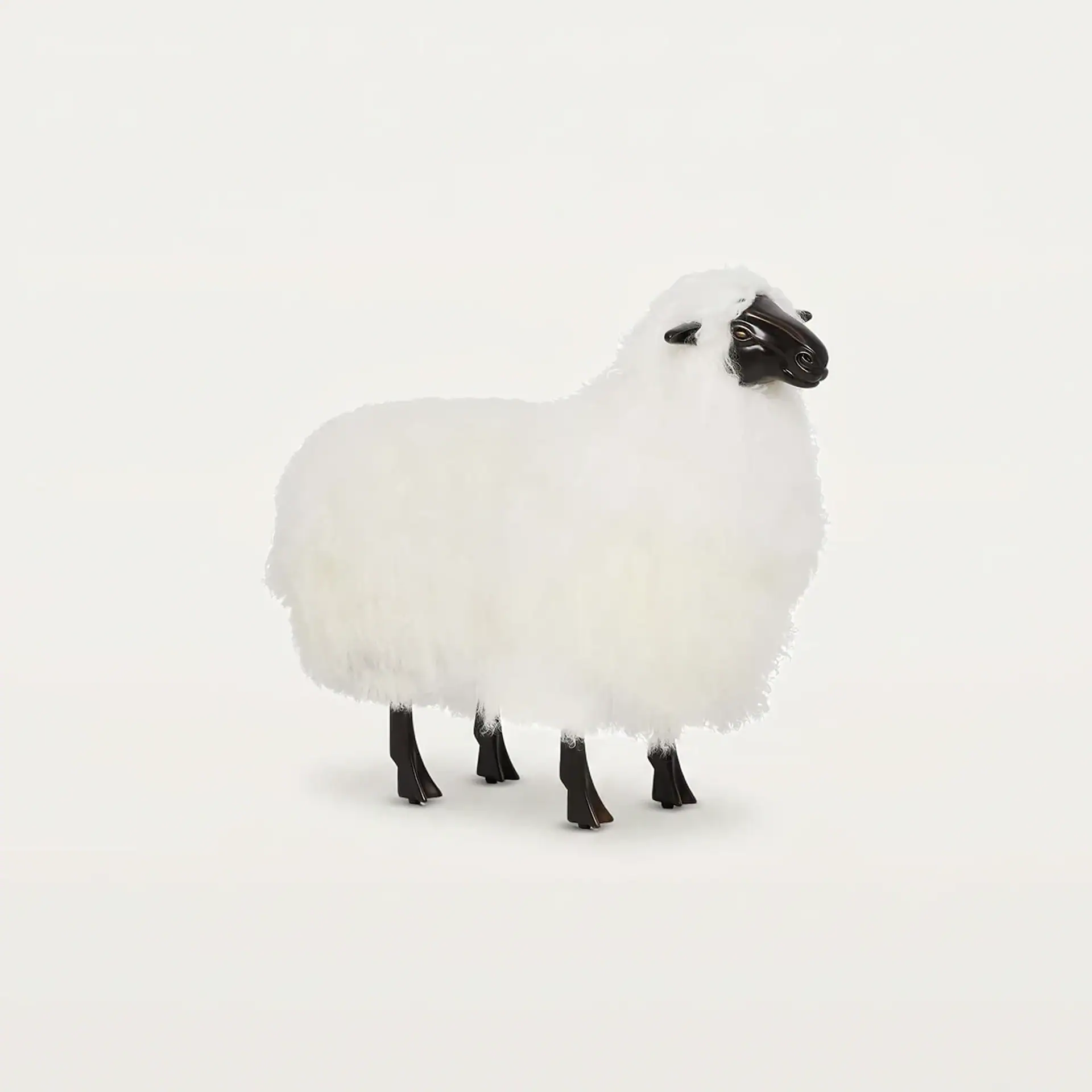 A white fluffy sheep figurine with a dark brown head and legs, standing on a light background.
